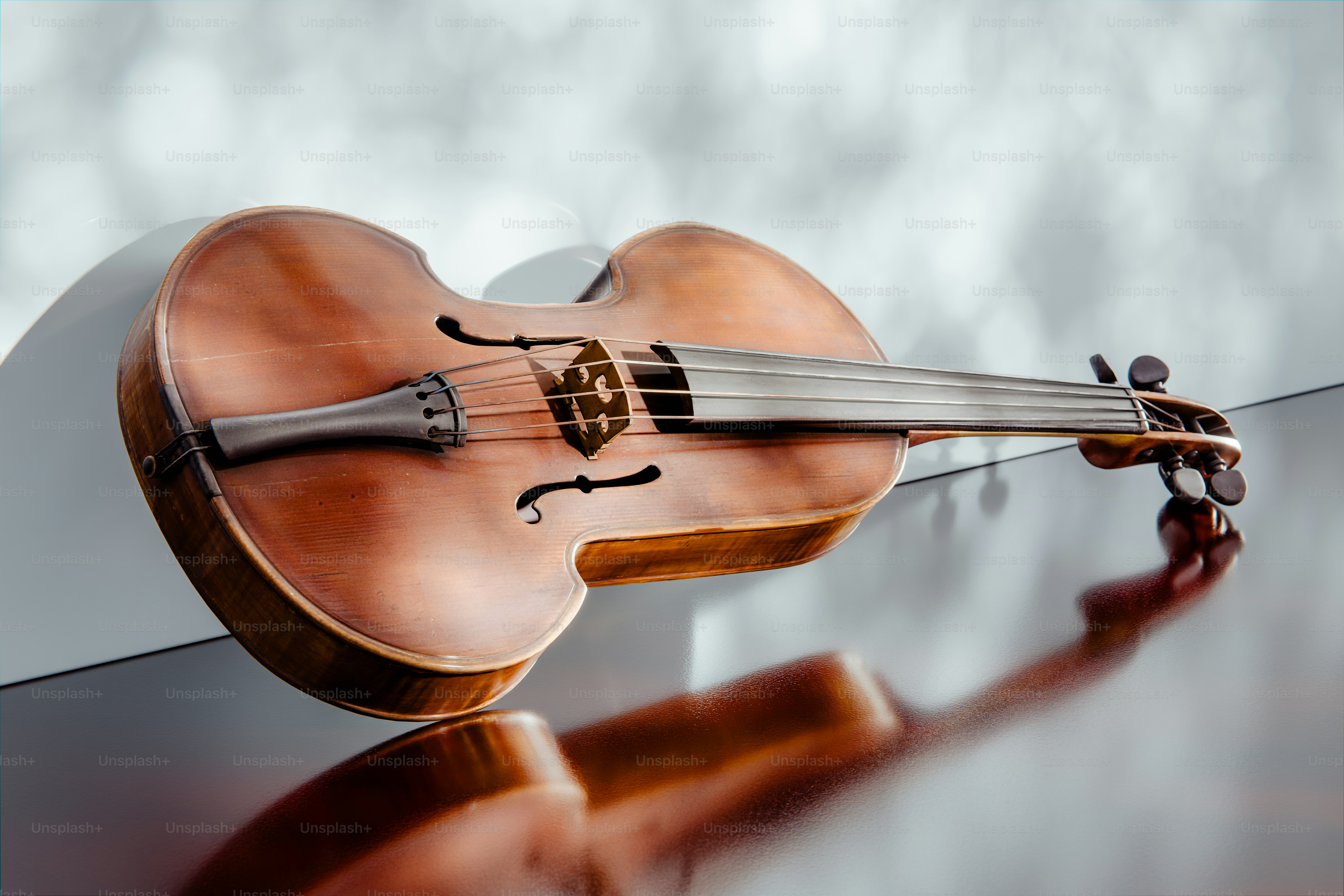 A wooden viola rests on a reflective surface