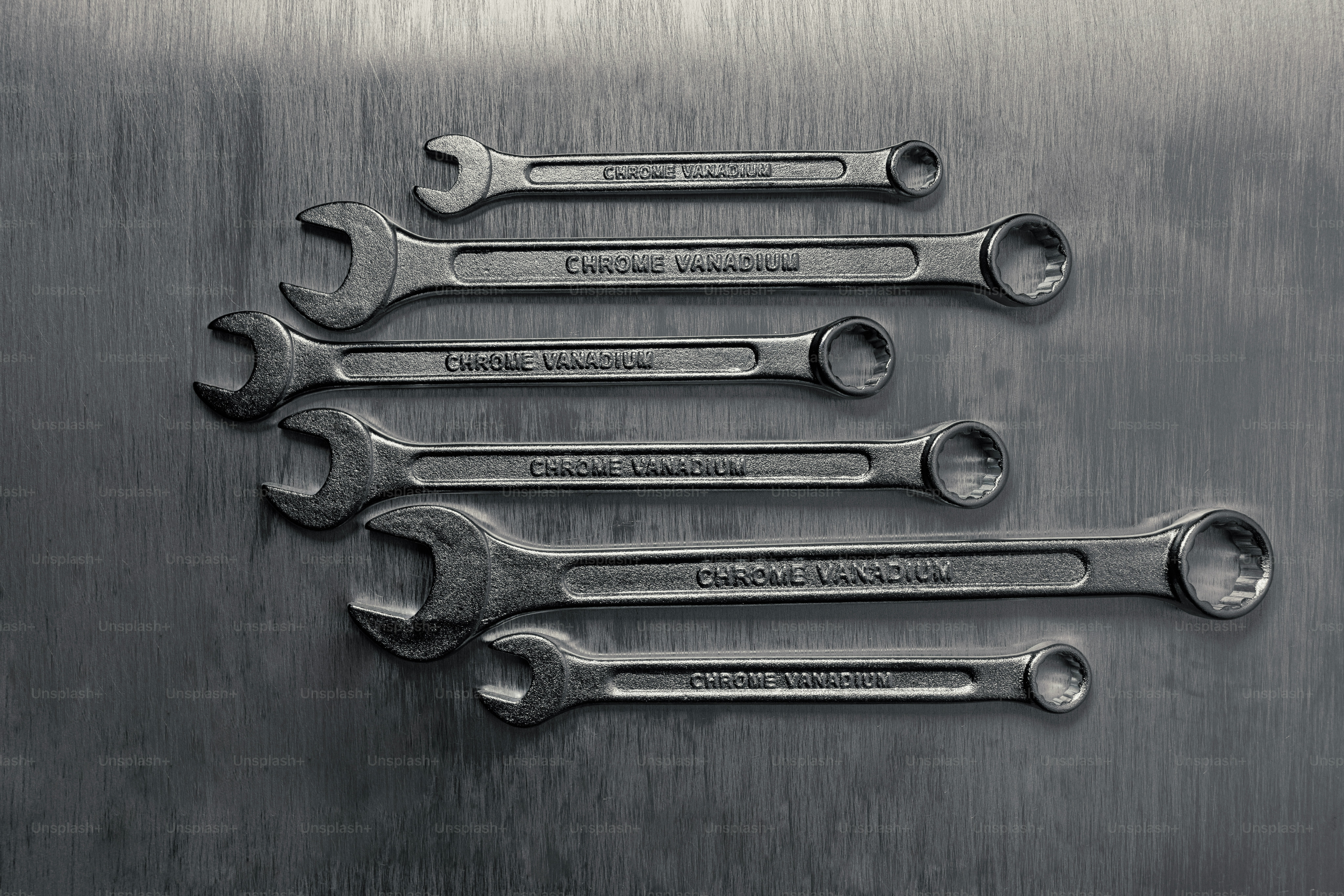 Set of metal wrenches arranged on a textured surface