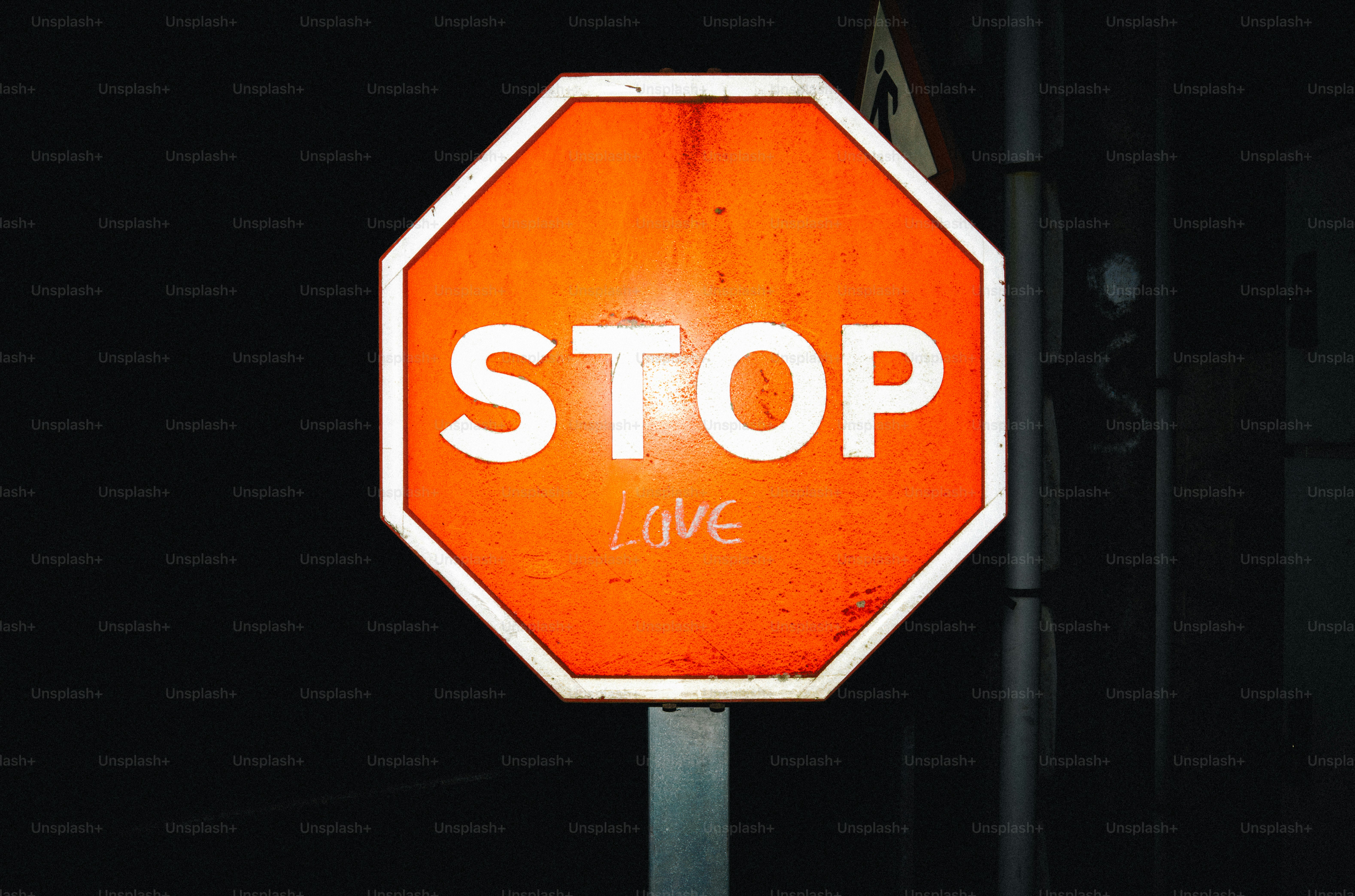 Orange stop sign with graffiti at night