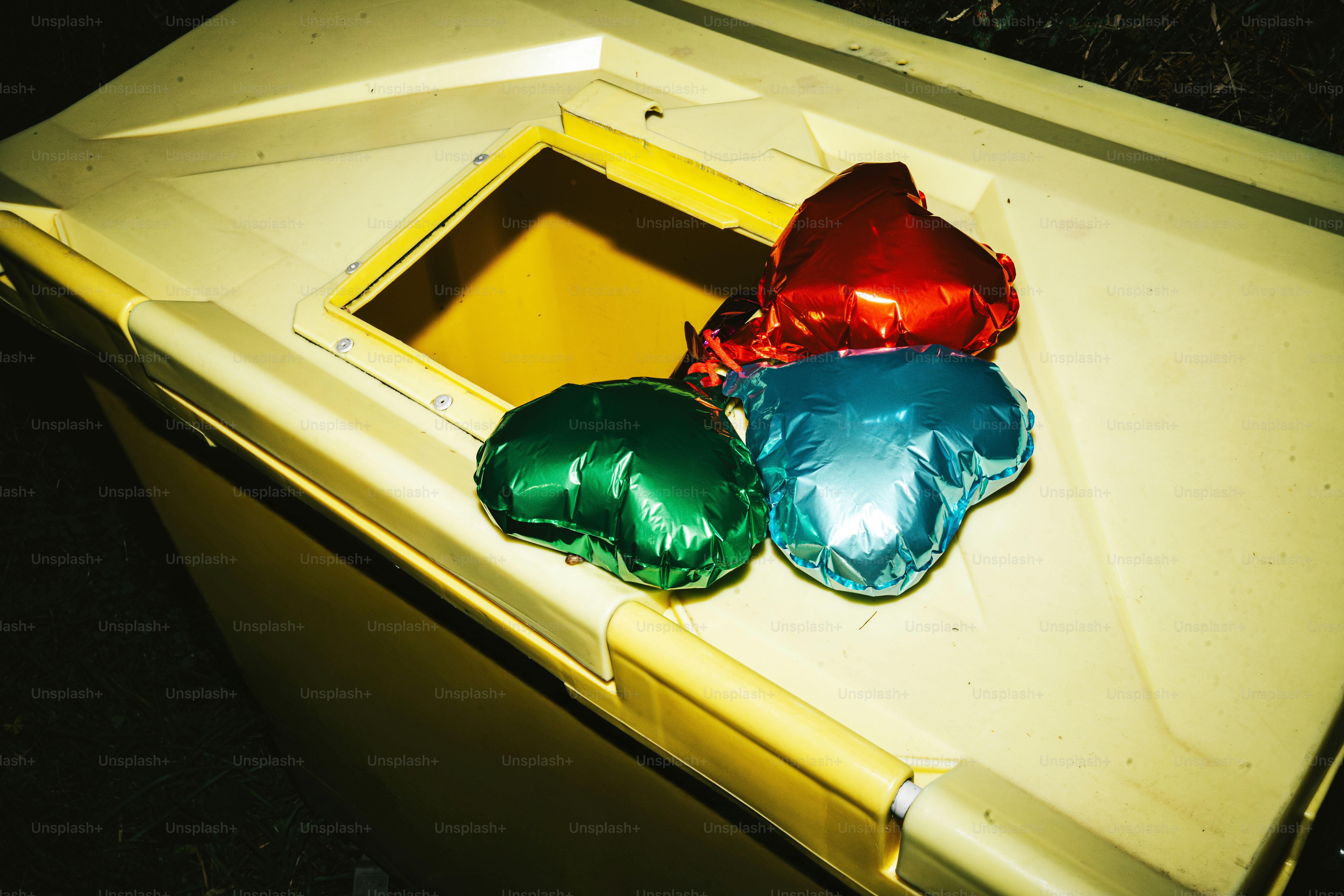 Four colorful balloons on a yellow bin