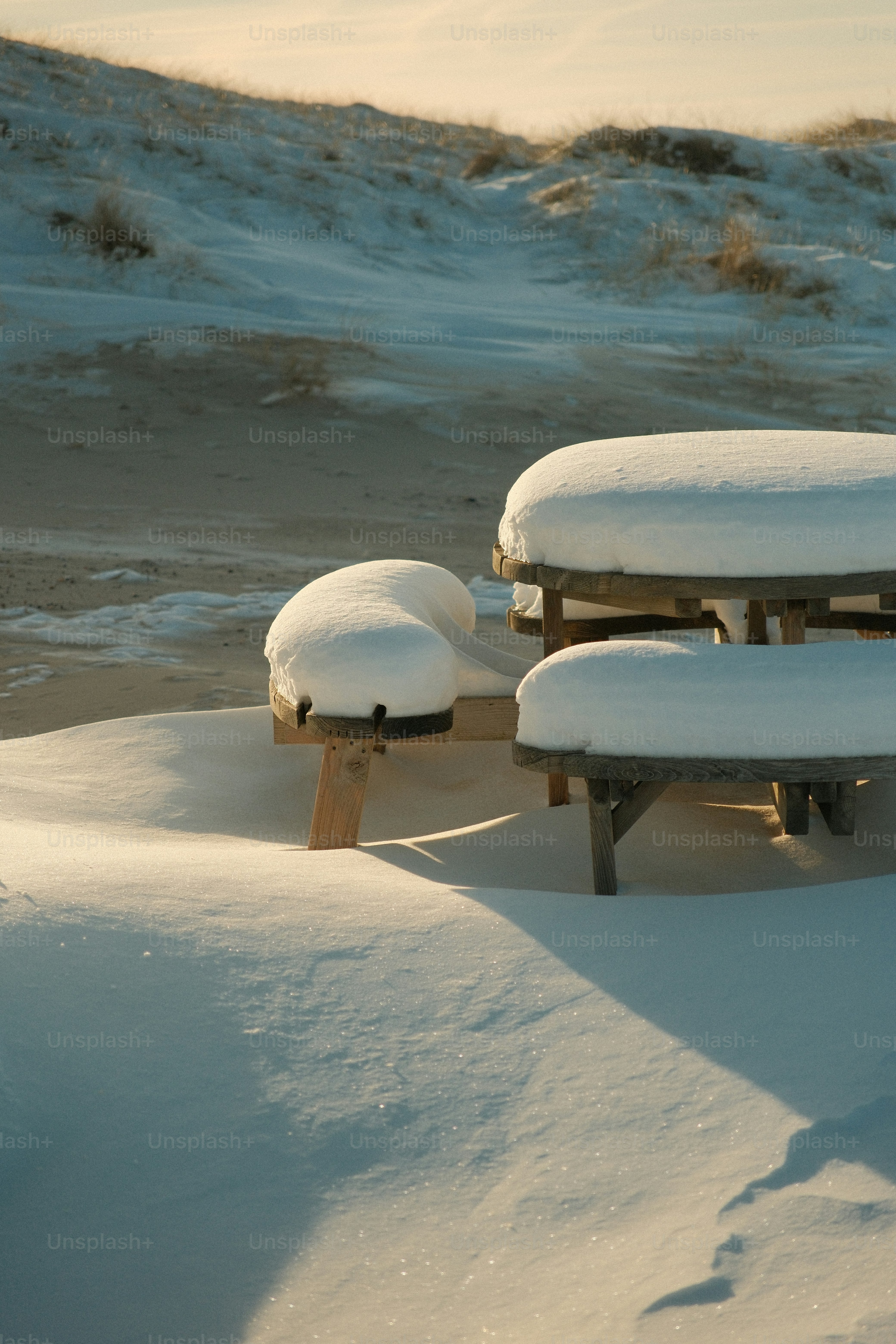 Snow covered picnic table on a sandy beach.