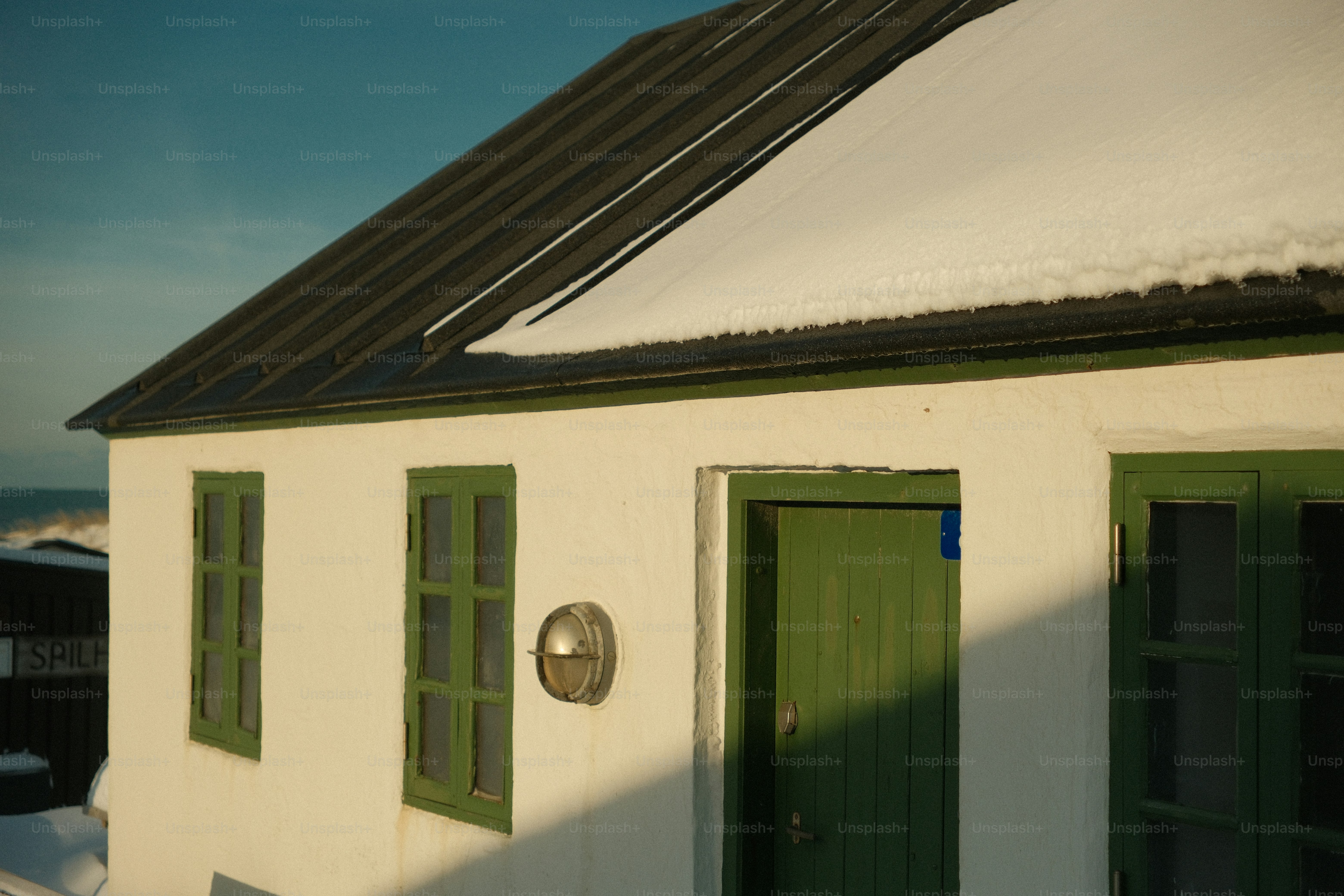 White building with green doors and windows covered in snow