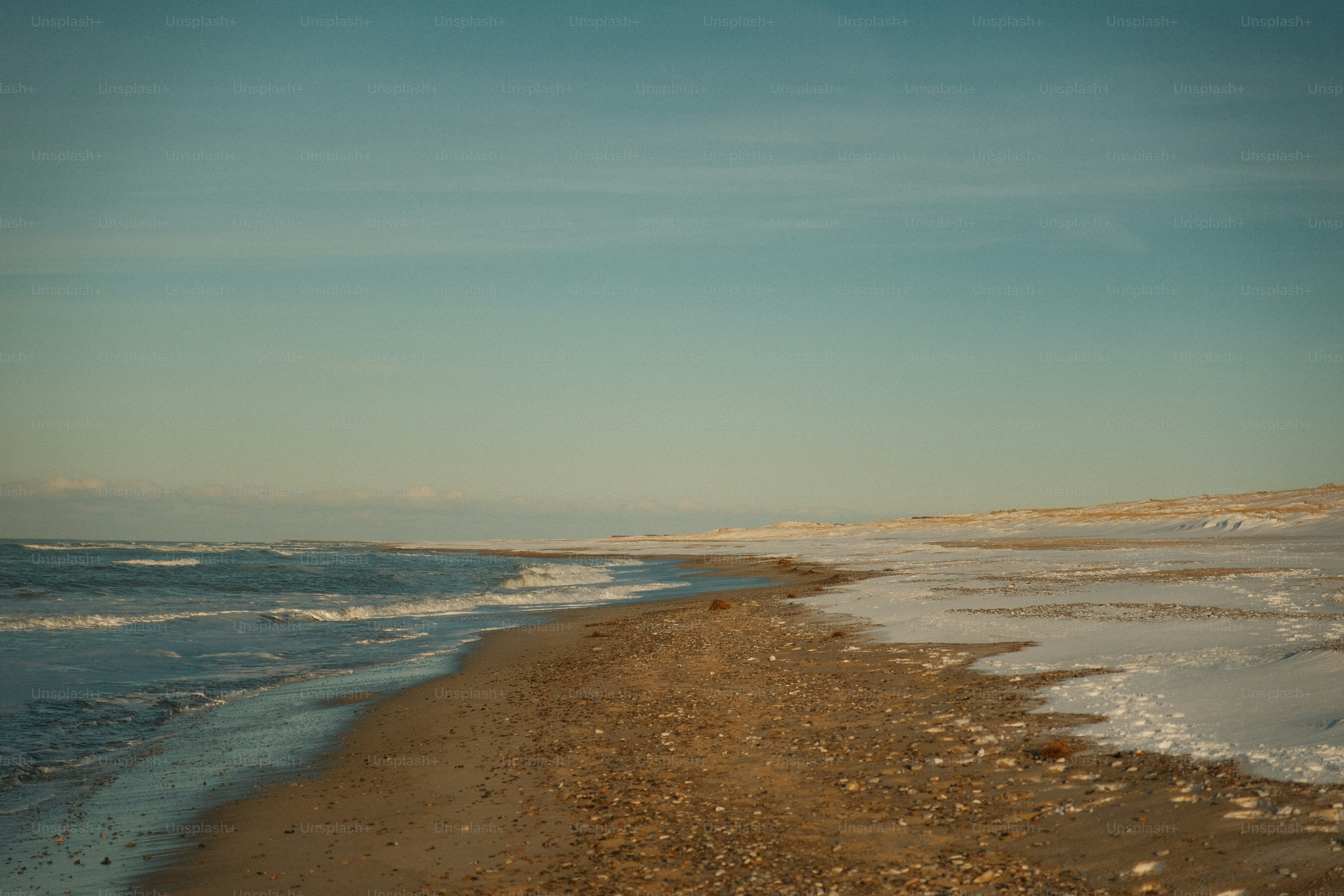 Une plage d’hiver aux vagues glacées et au sable enneigé