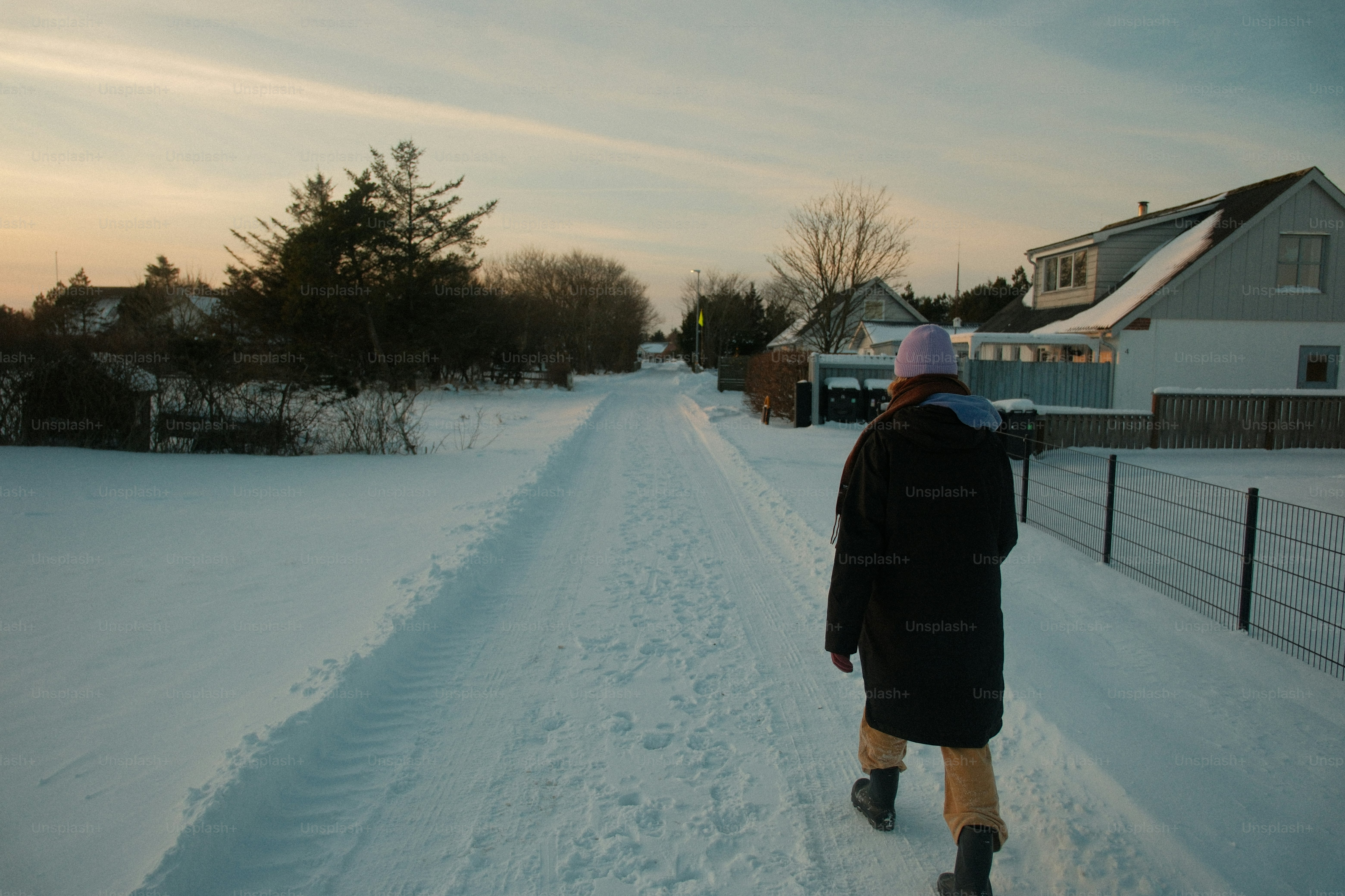 Person walks down a snowy path near houses.