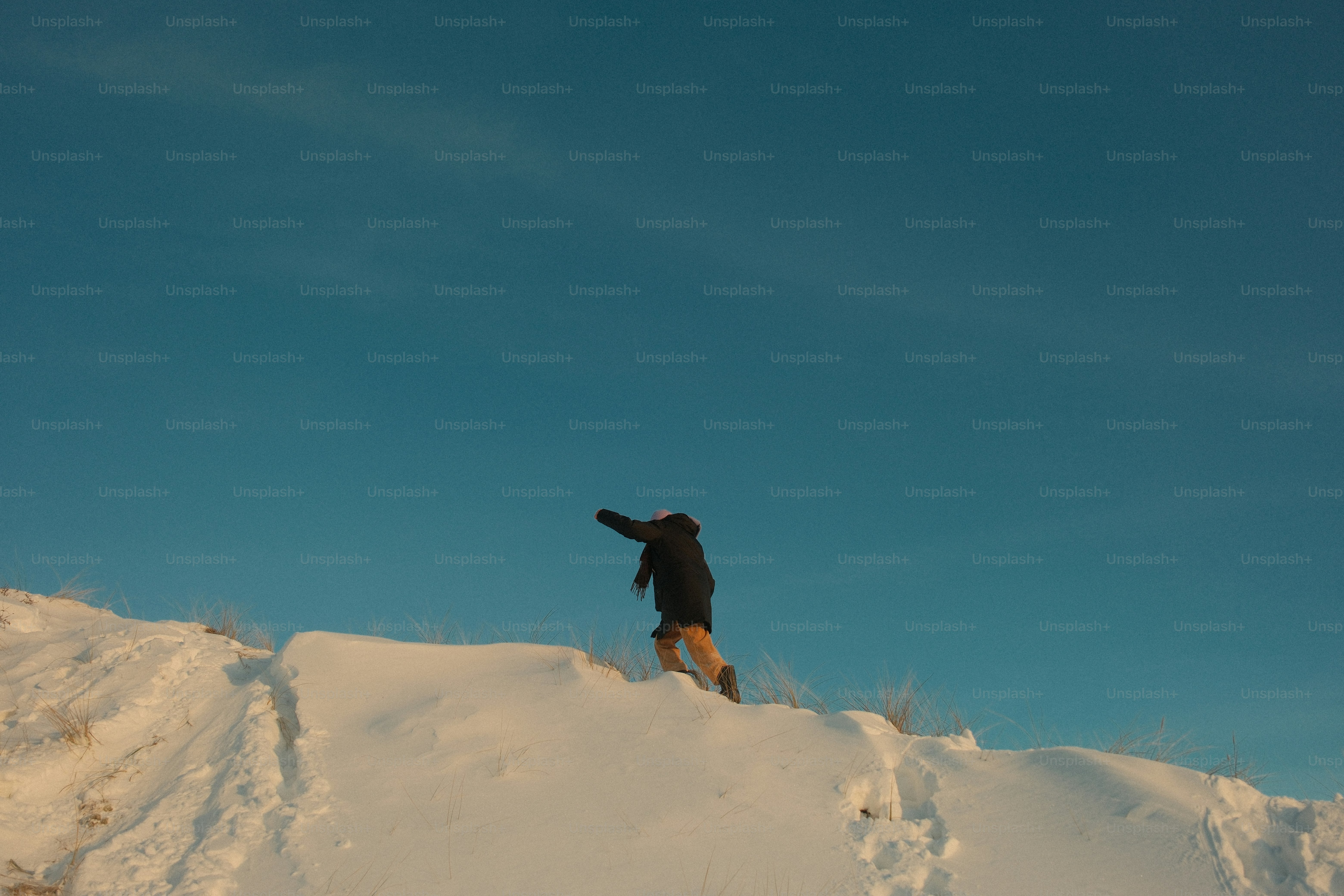 Personne debout sur une colline enneigée sous un ciel bleu clair