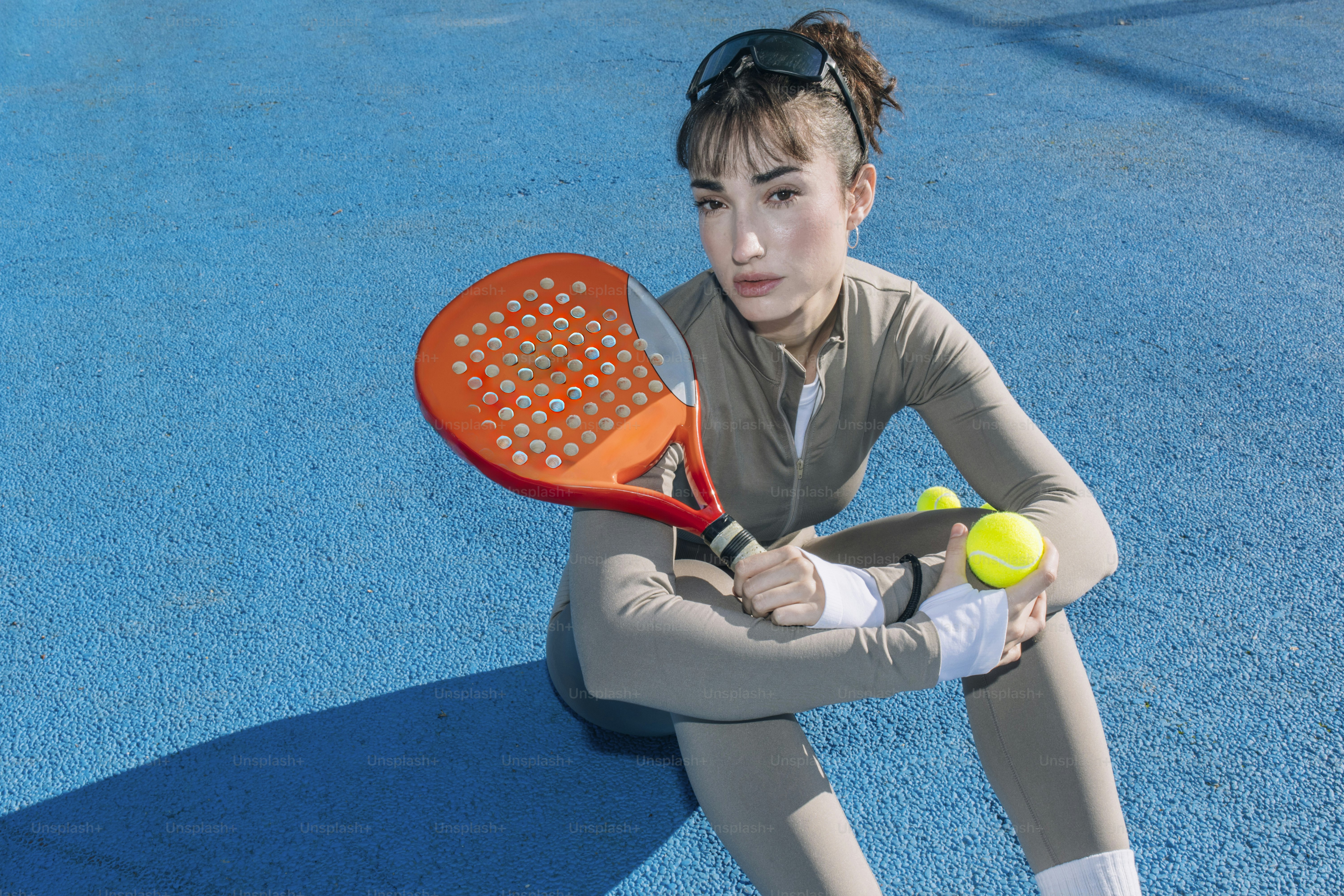 Junge Frau mit Padelschläger und Bällen auf dem Platz