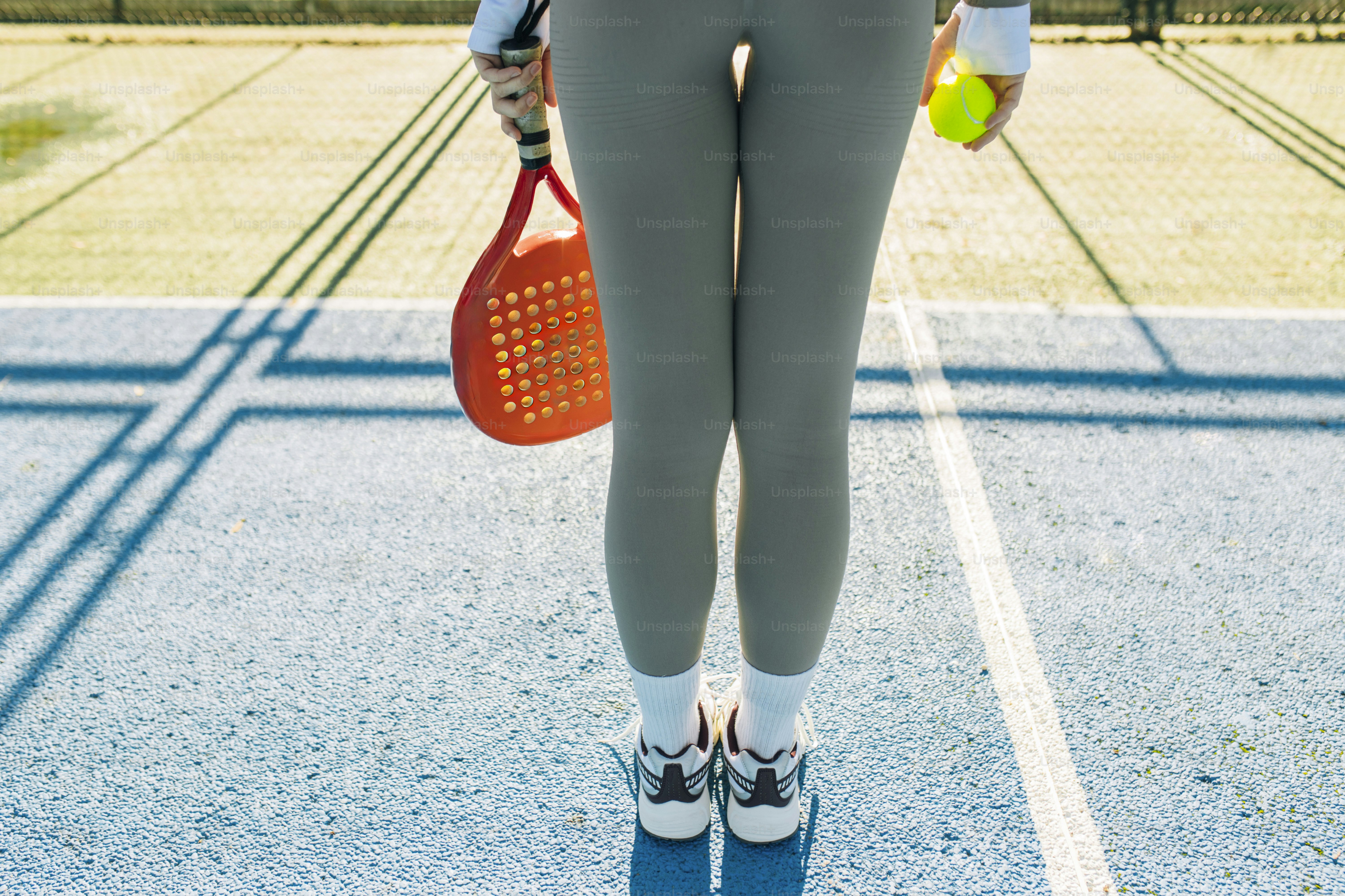 Frau, die ein Paddel und einen Ball auf einem Platz hält