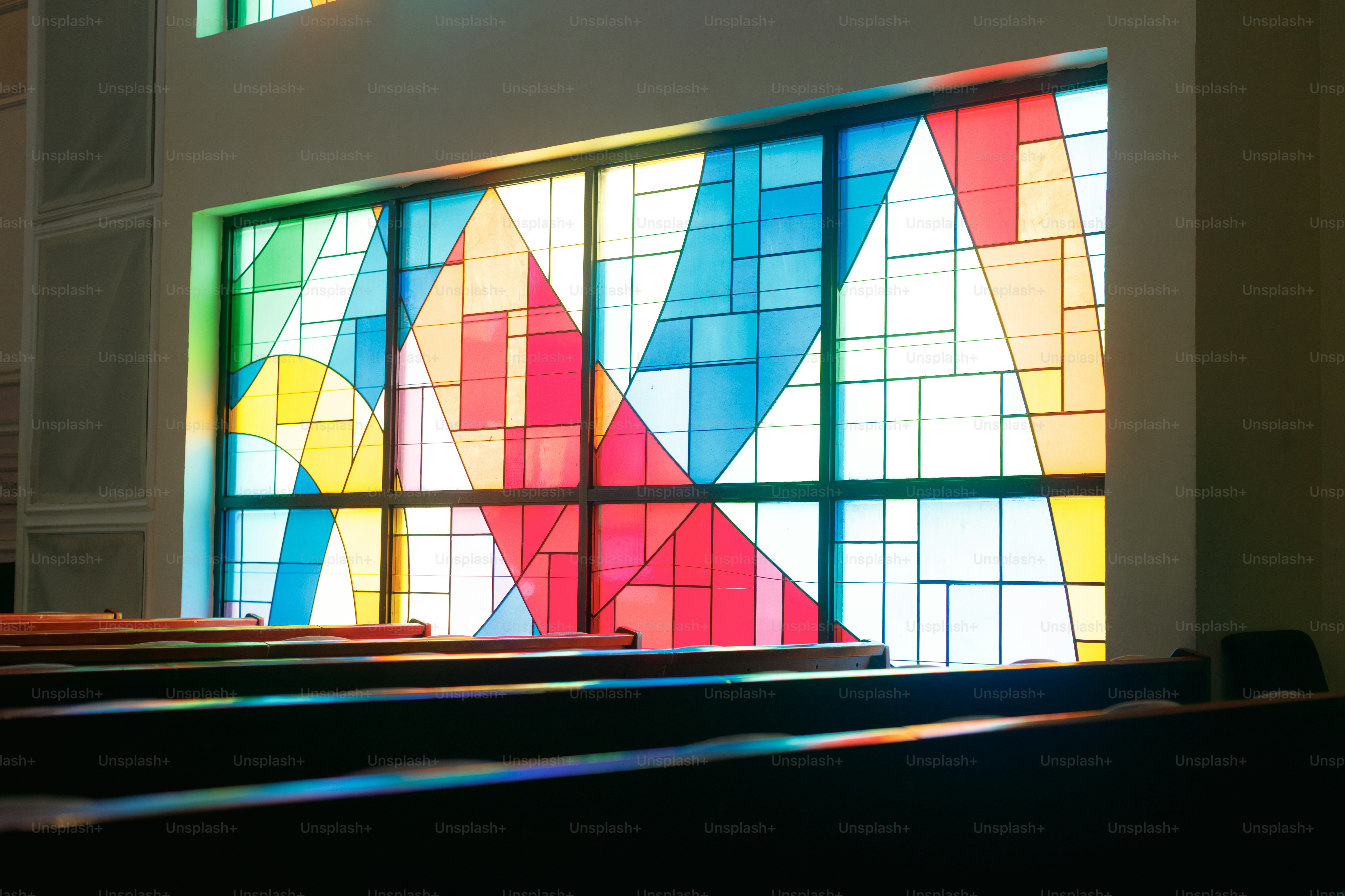 Colorful stained glass window casting light on benches