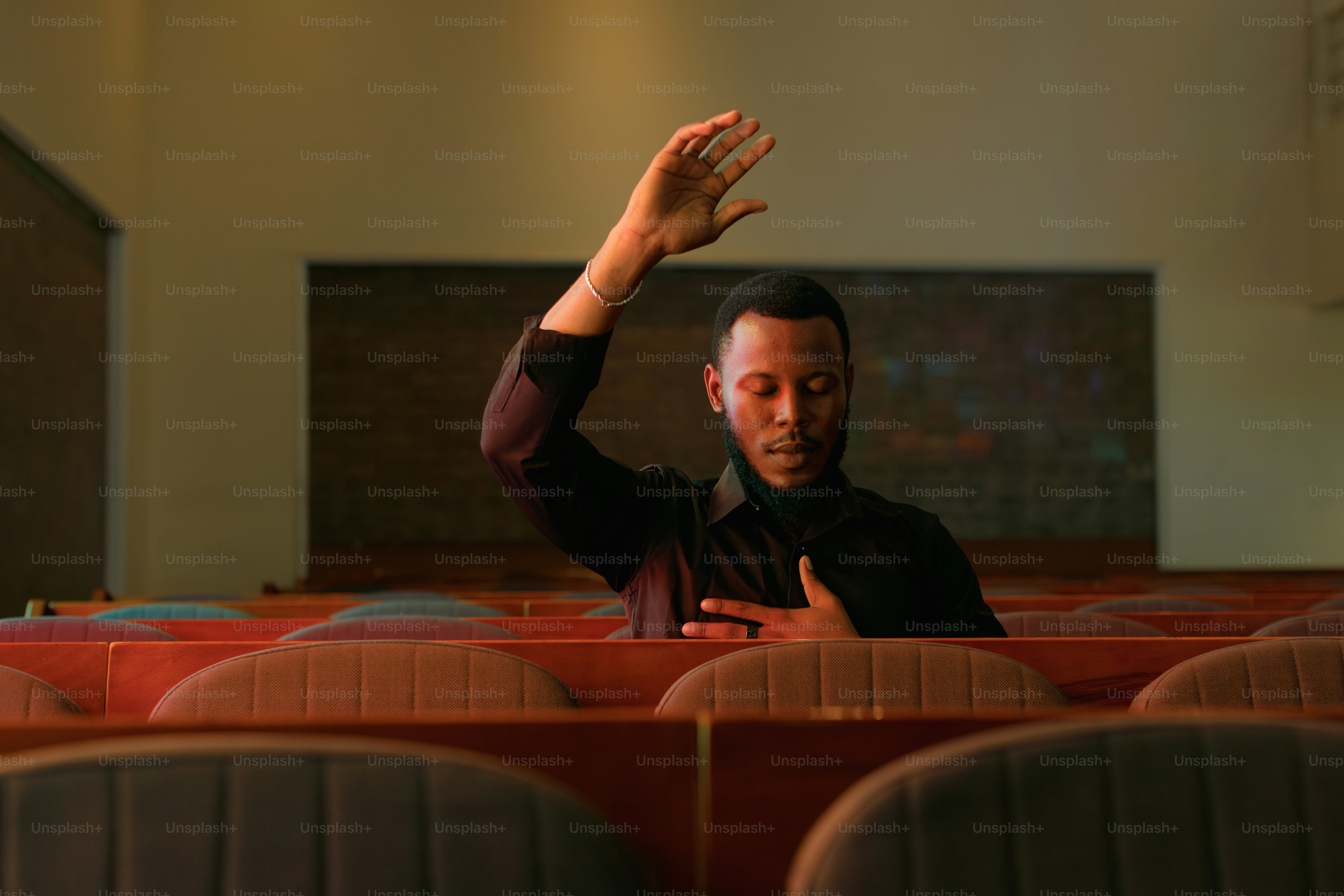 Man with hand raised in empty auditorium