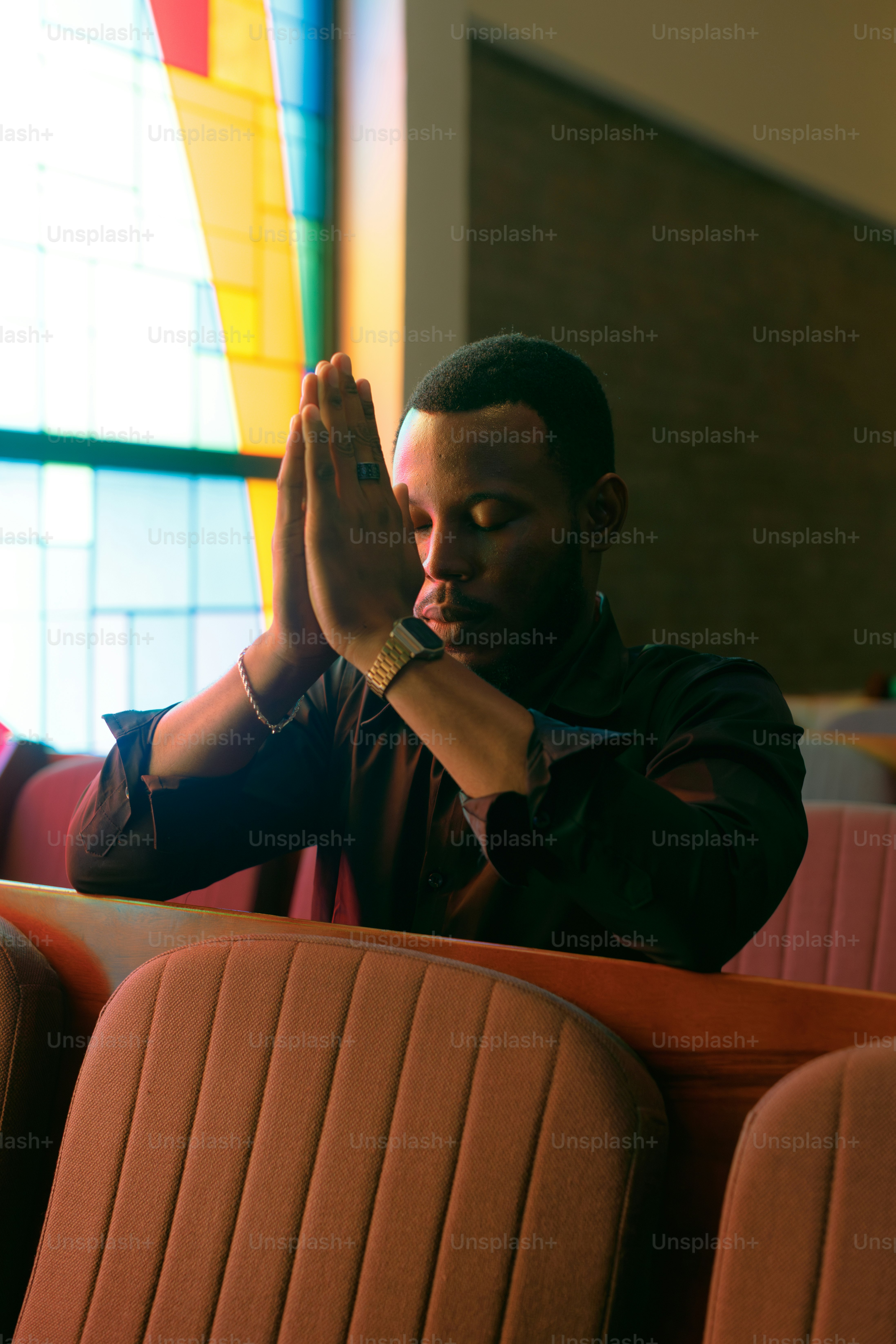 A man praying with hands clasped in a church.