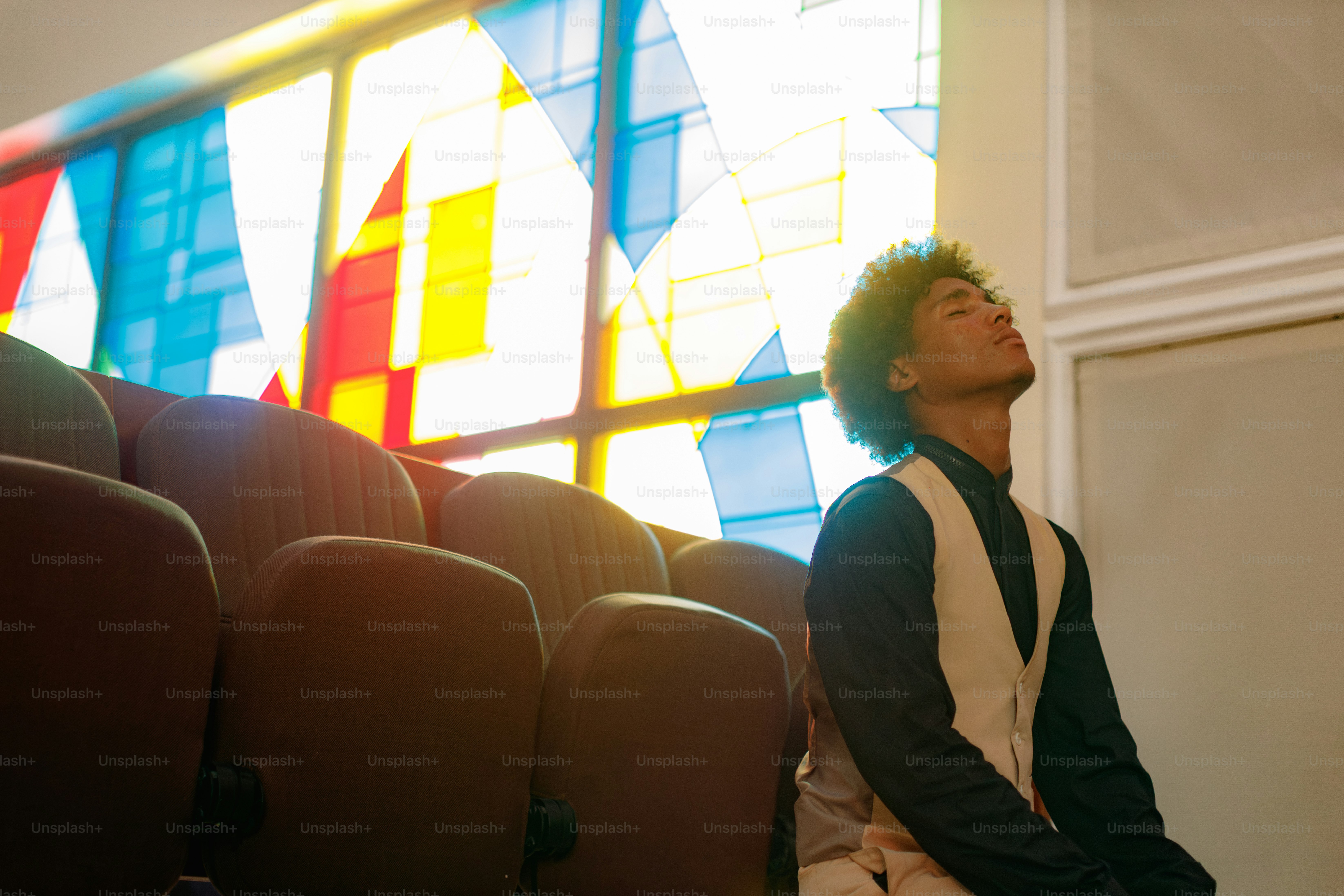 A young man looking up at stained glass windows