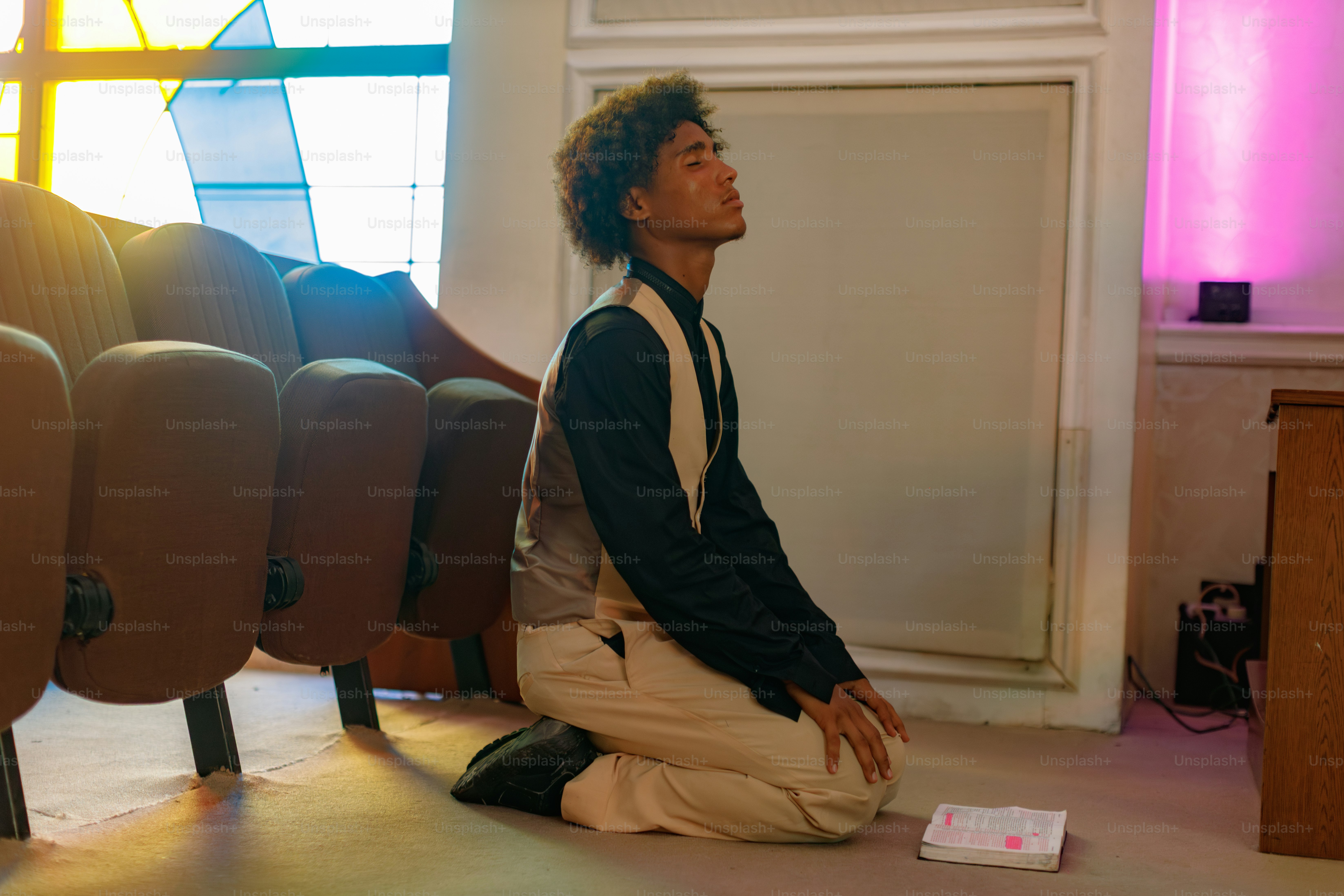 教会で若い男性がひざまずいて祈っている。