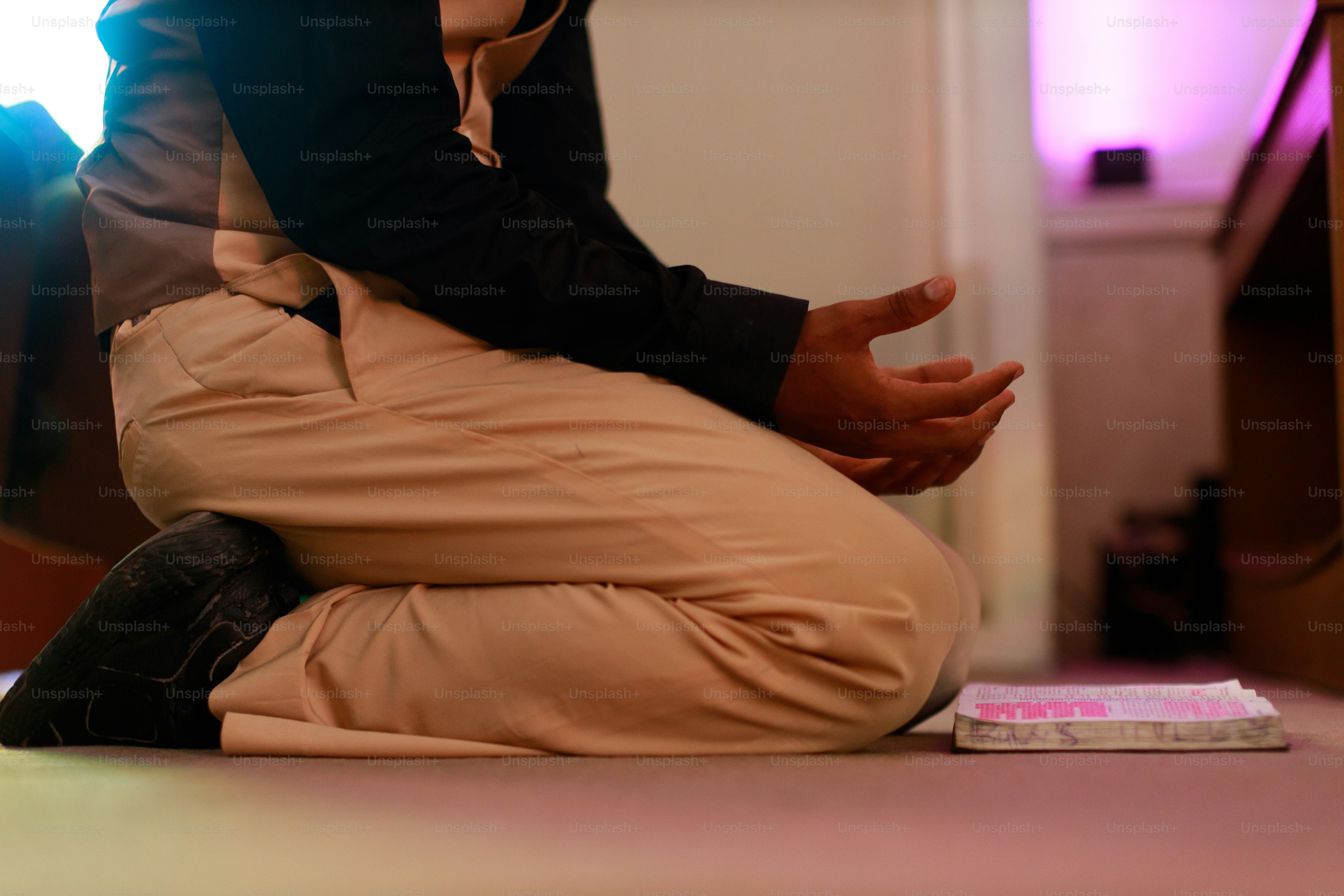 本のそばで手を開いてひざまずいている人。