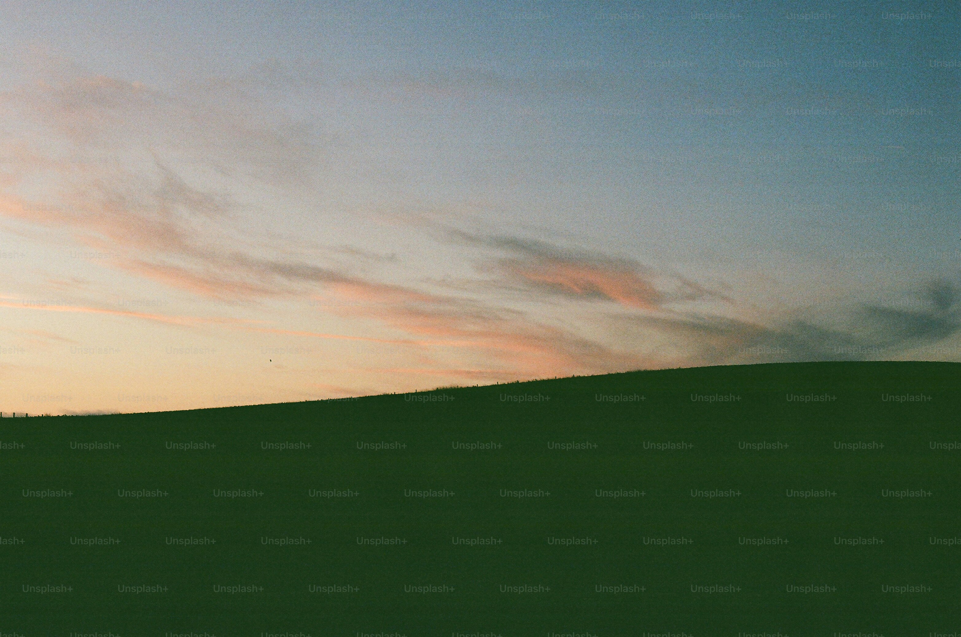 Green rolling hills under a pastel sky
