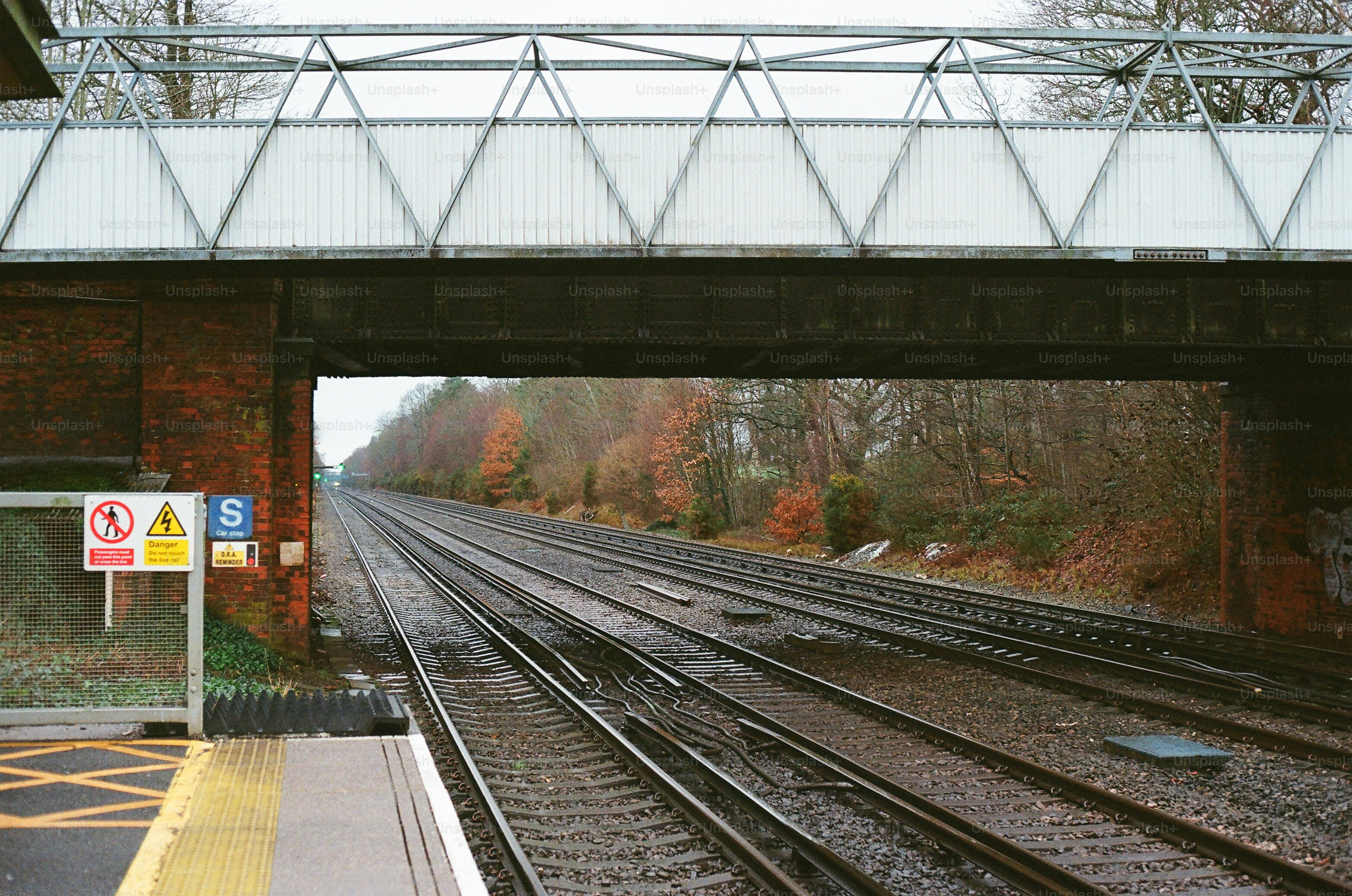 Train tracks pass under a pedestrian bridge