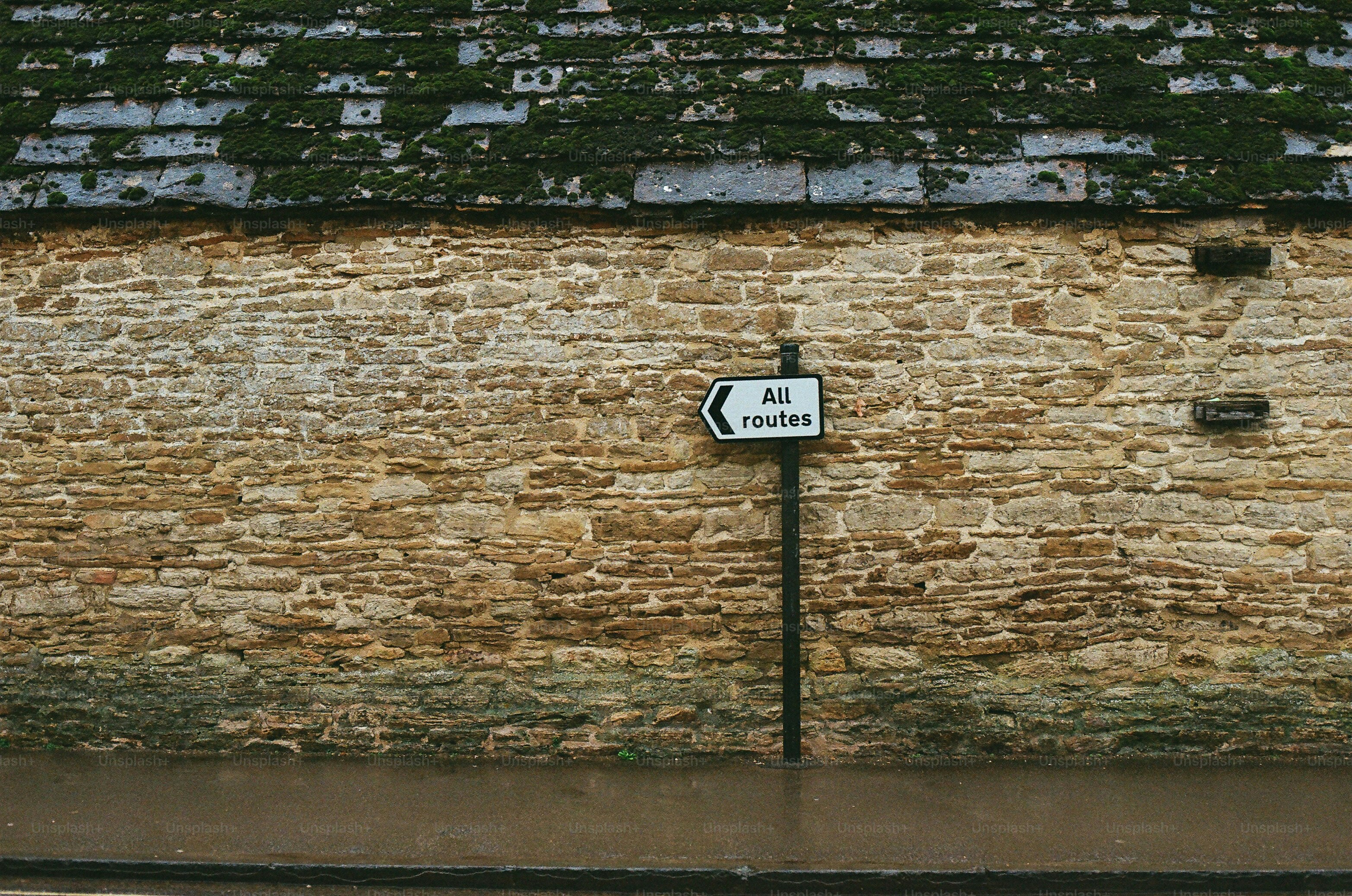 A sign points to all routes on a stone wall.