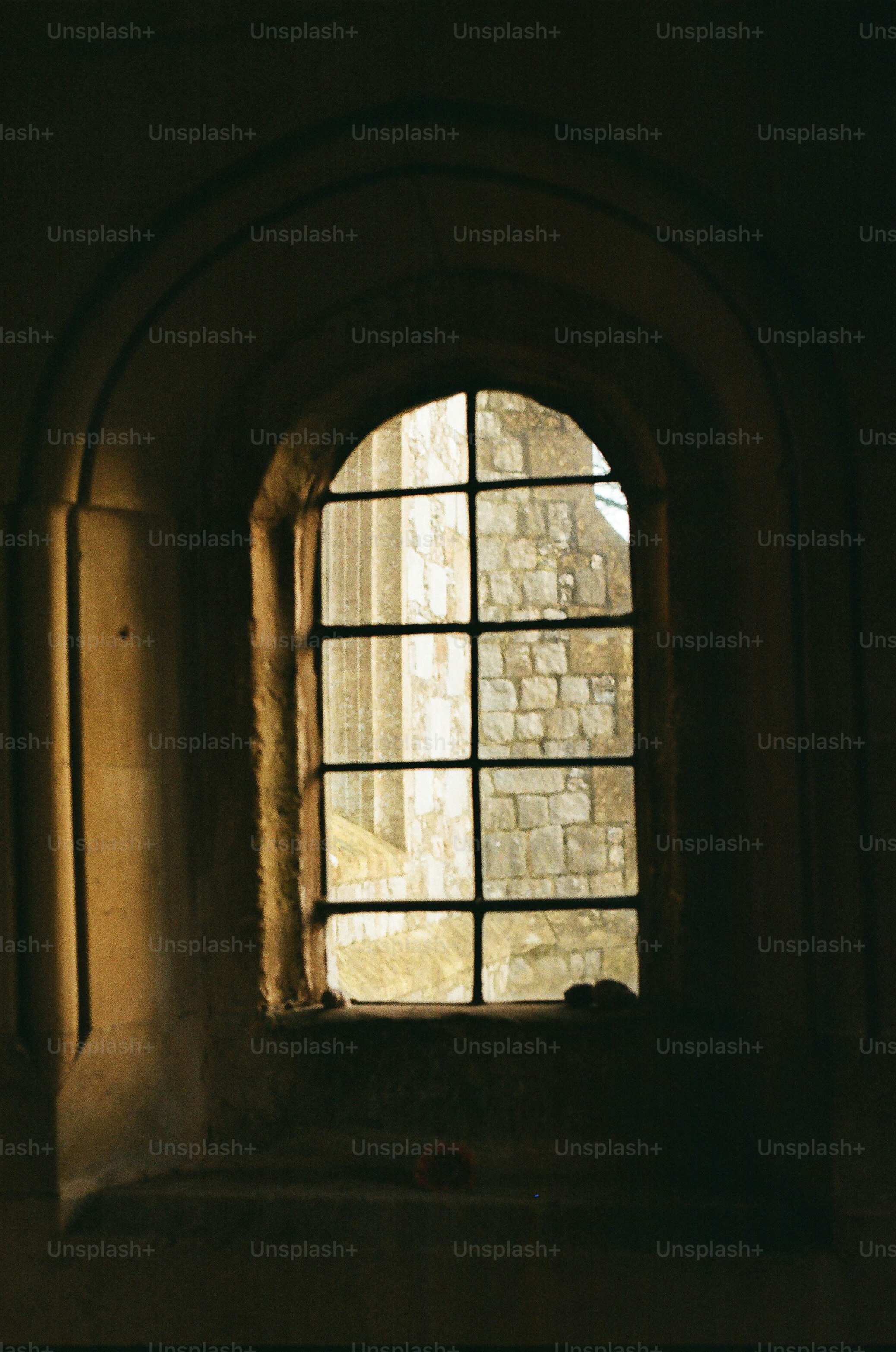 Janela arqueada com prédio de pedra visível do lado de fora