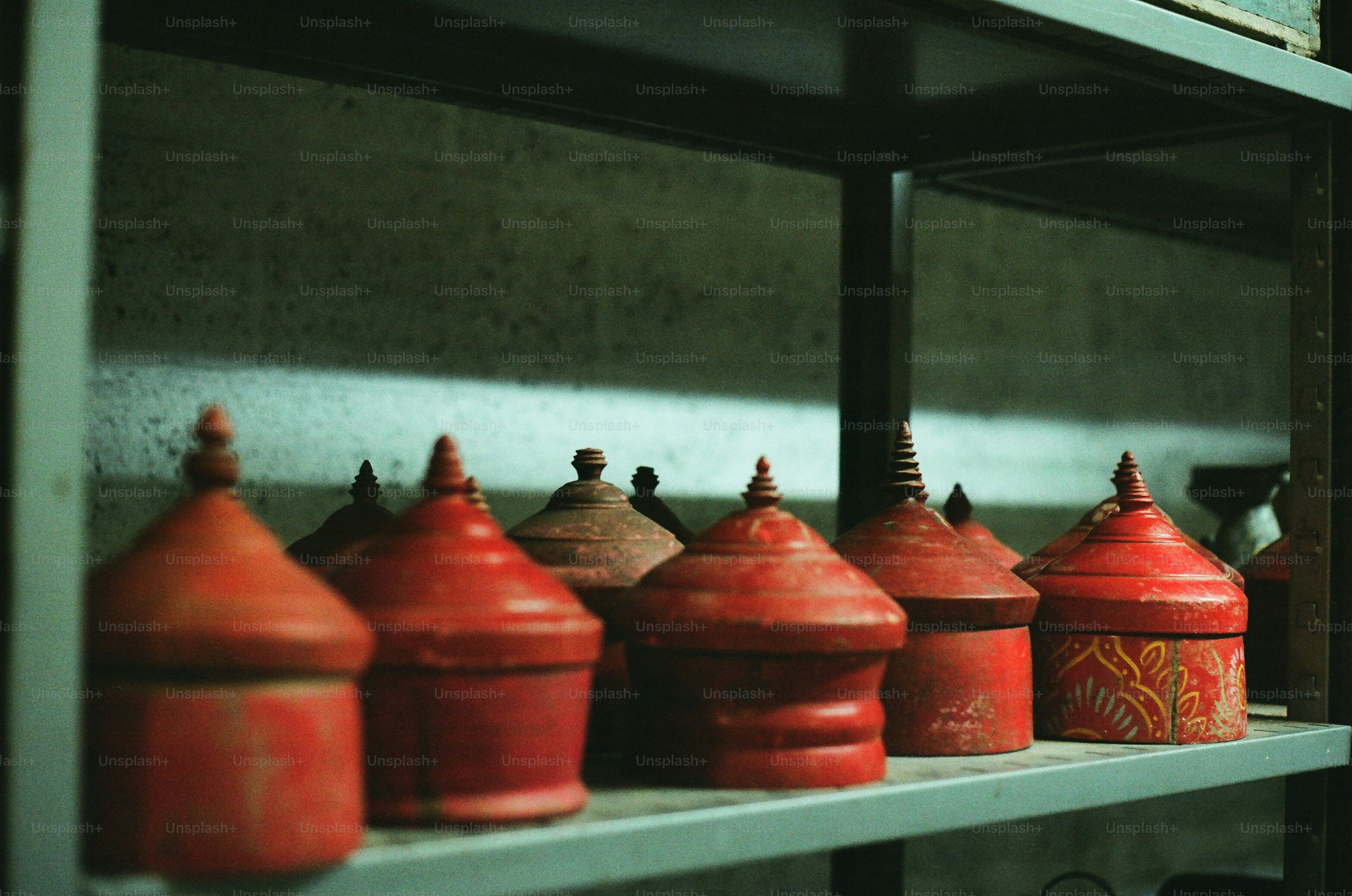 Several red containers with pointed lids on a shelf.
