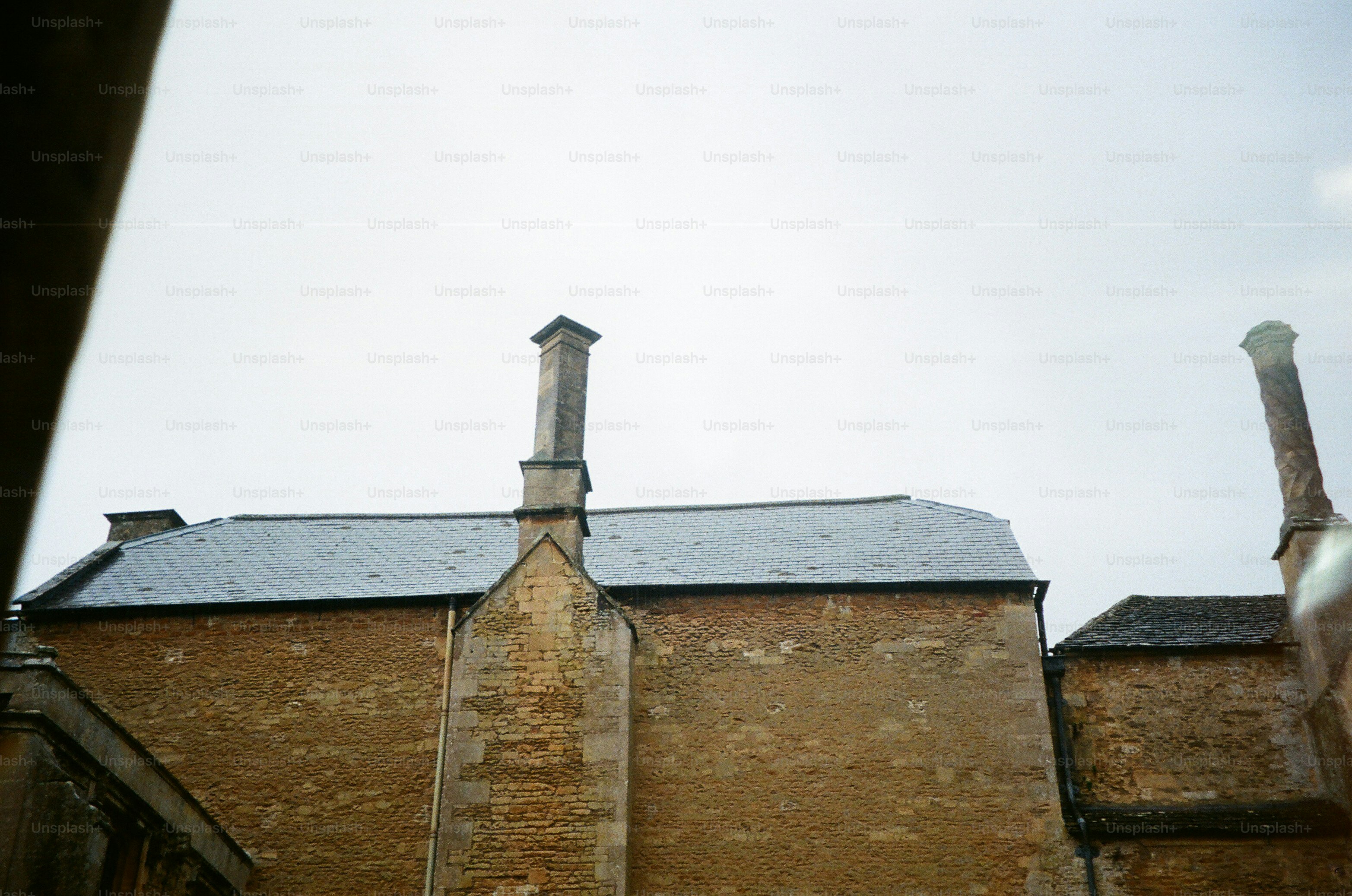 Two chimneys on a stone building under a cloudy sky