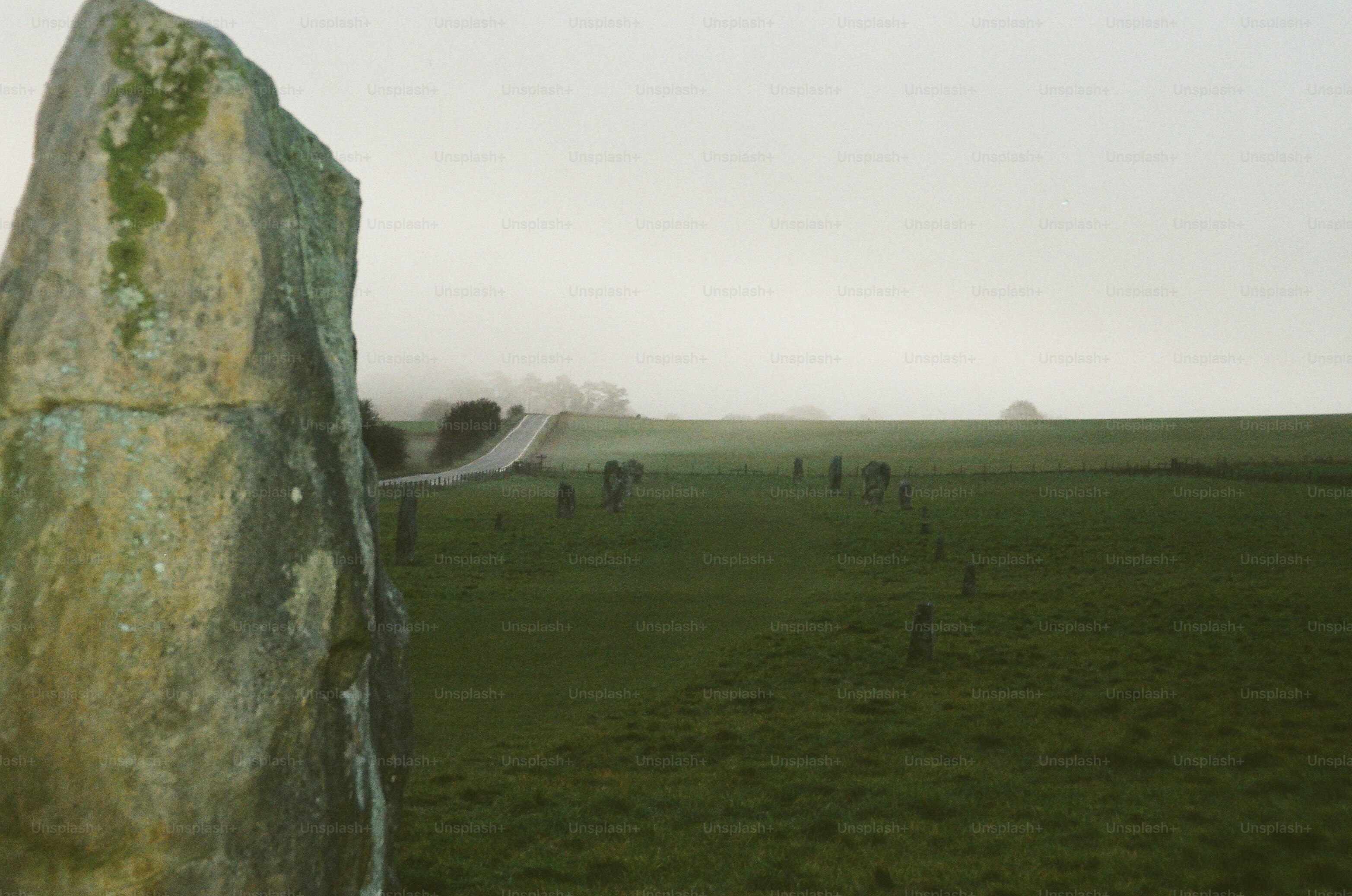Megaliths stand in a misty green field.