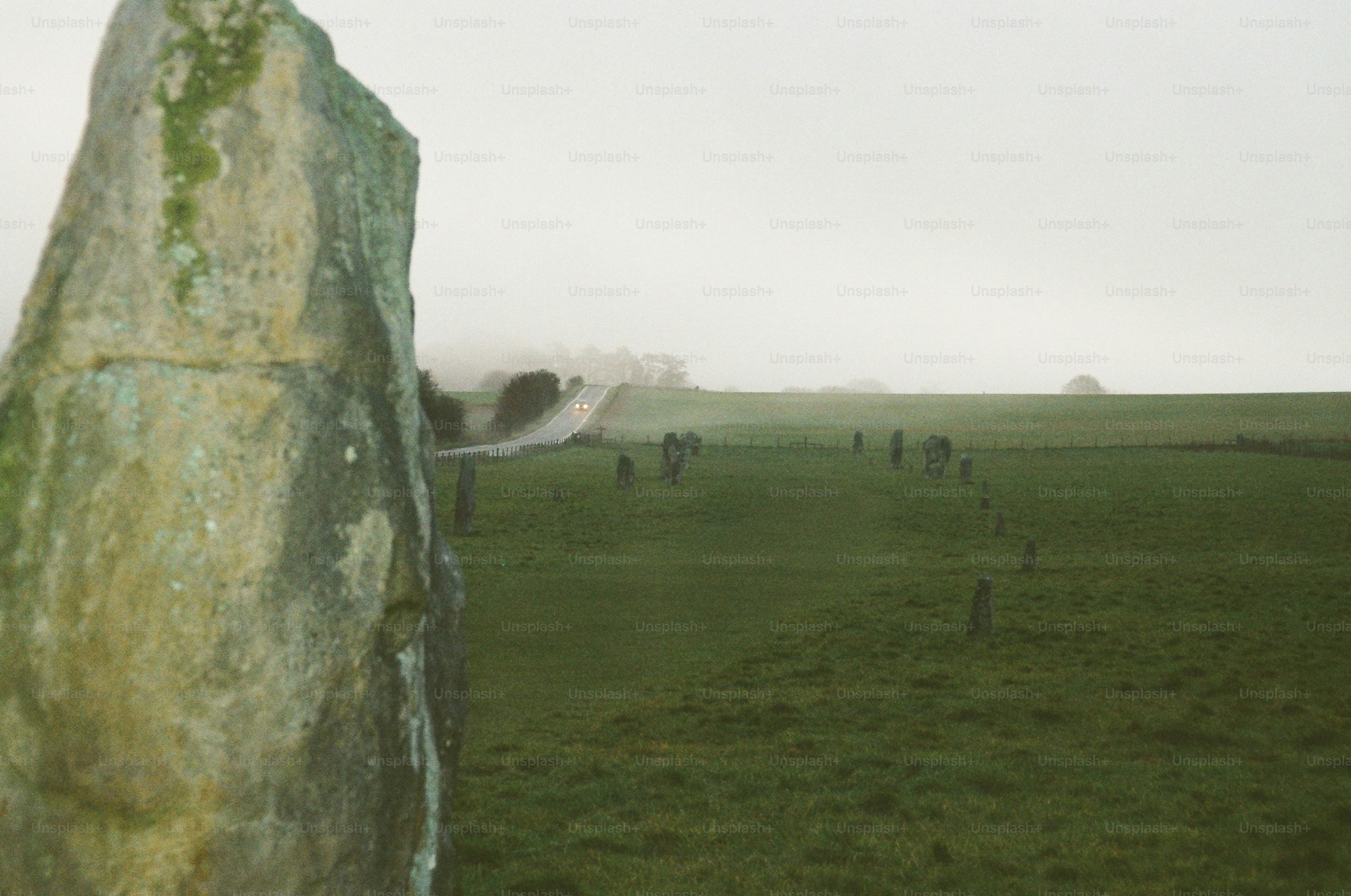 Megalithic standing stones in a misty green field.