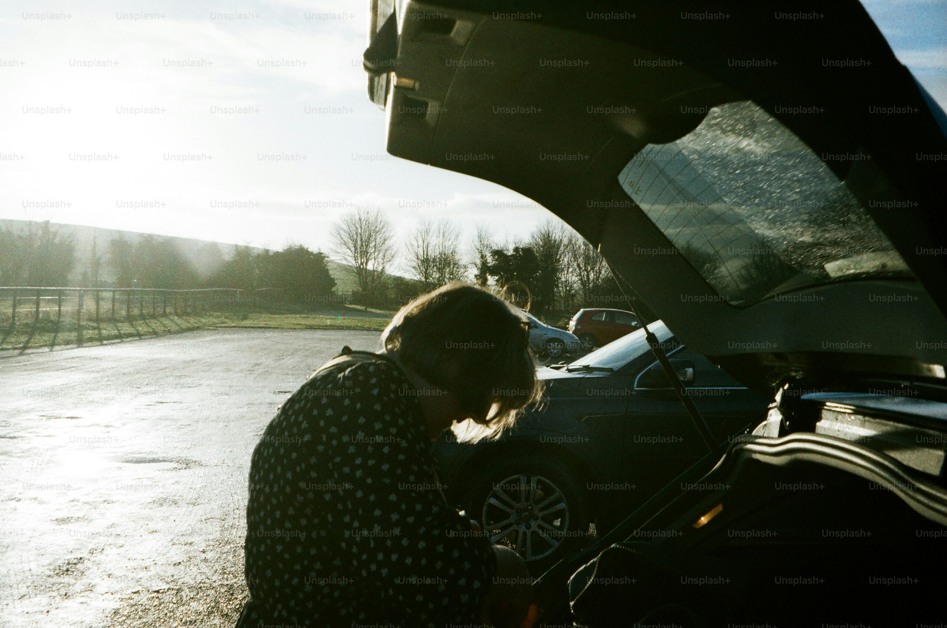 Person loading items into car trunk outdoors