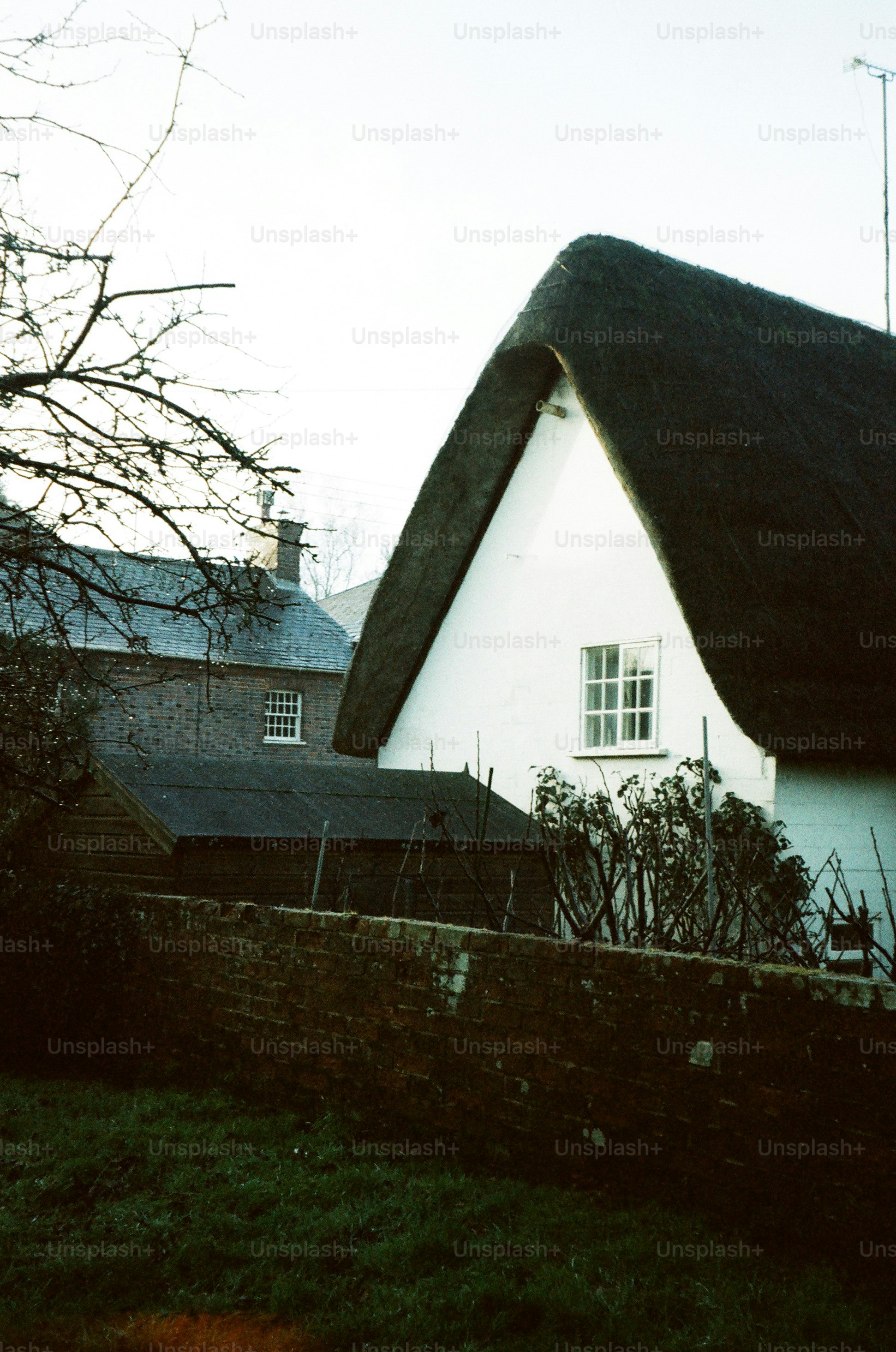 Strohdach-Häuschen mit Backsteinmauer und Bäumen