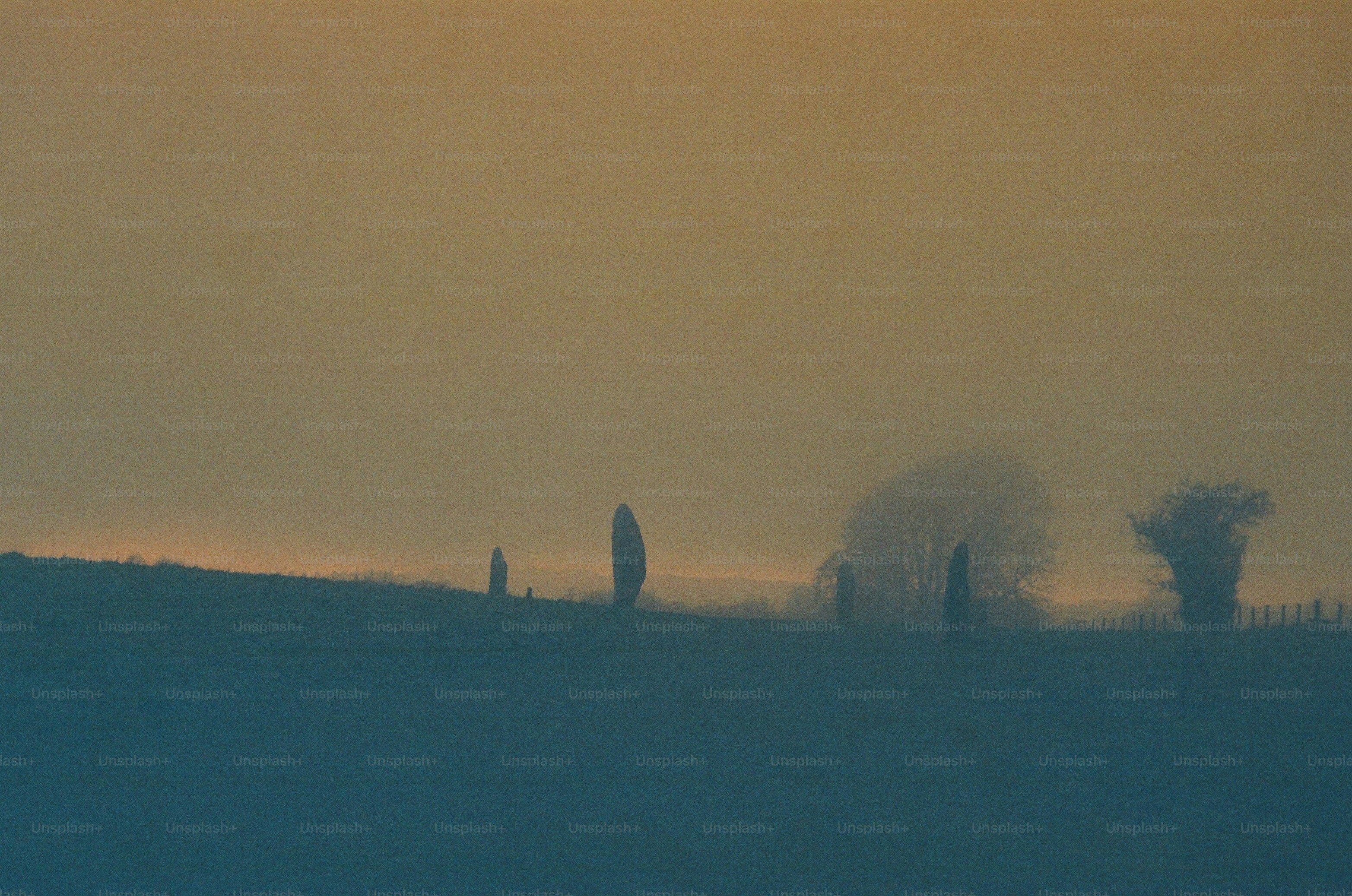 Misty sunrise over rolling hills with standing stones.