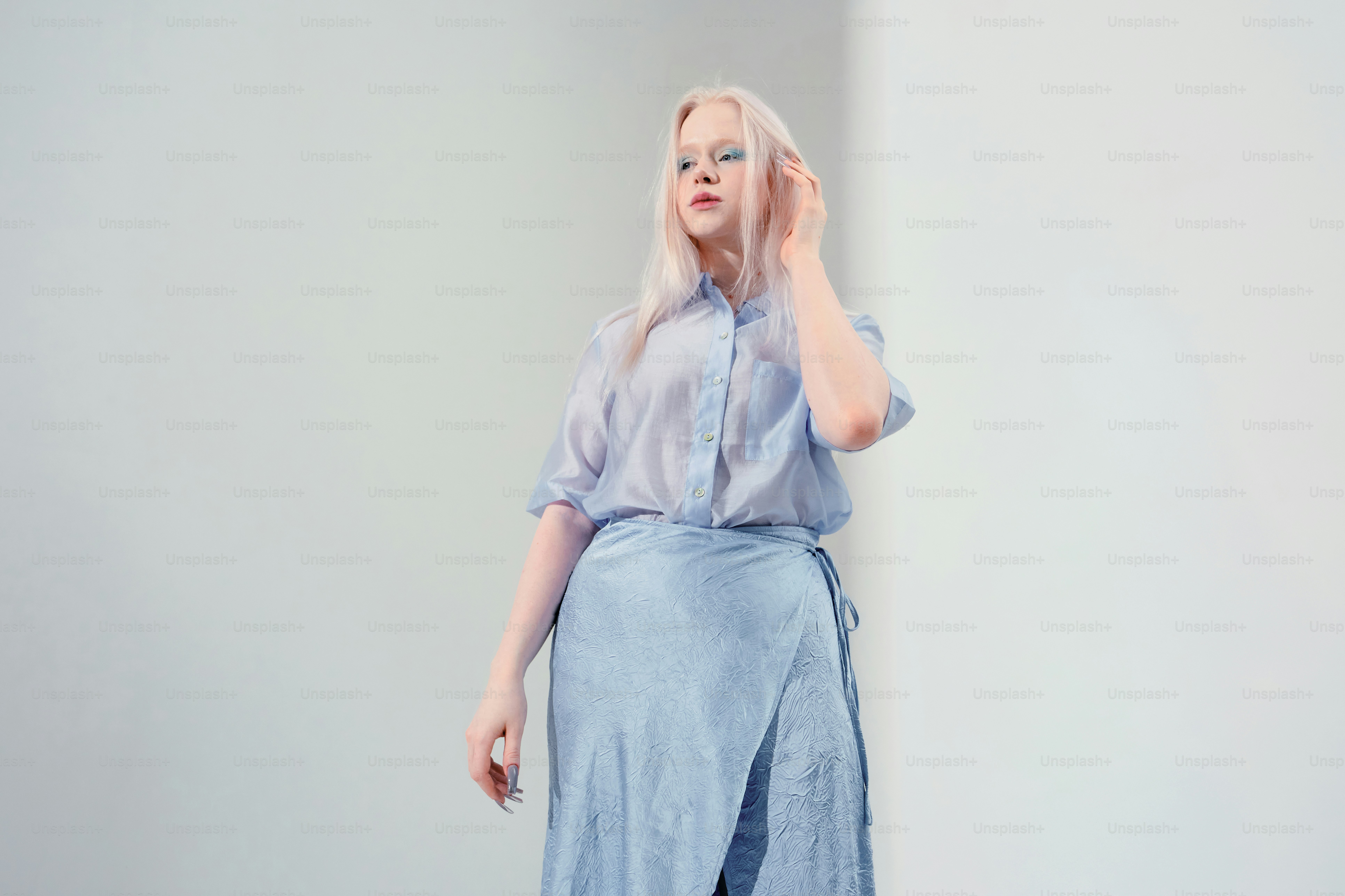 A woman in a blue shirt and skirt poses indoors. photo – Portrait Image ...