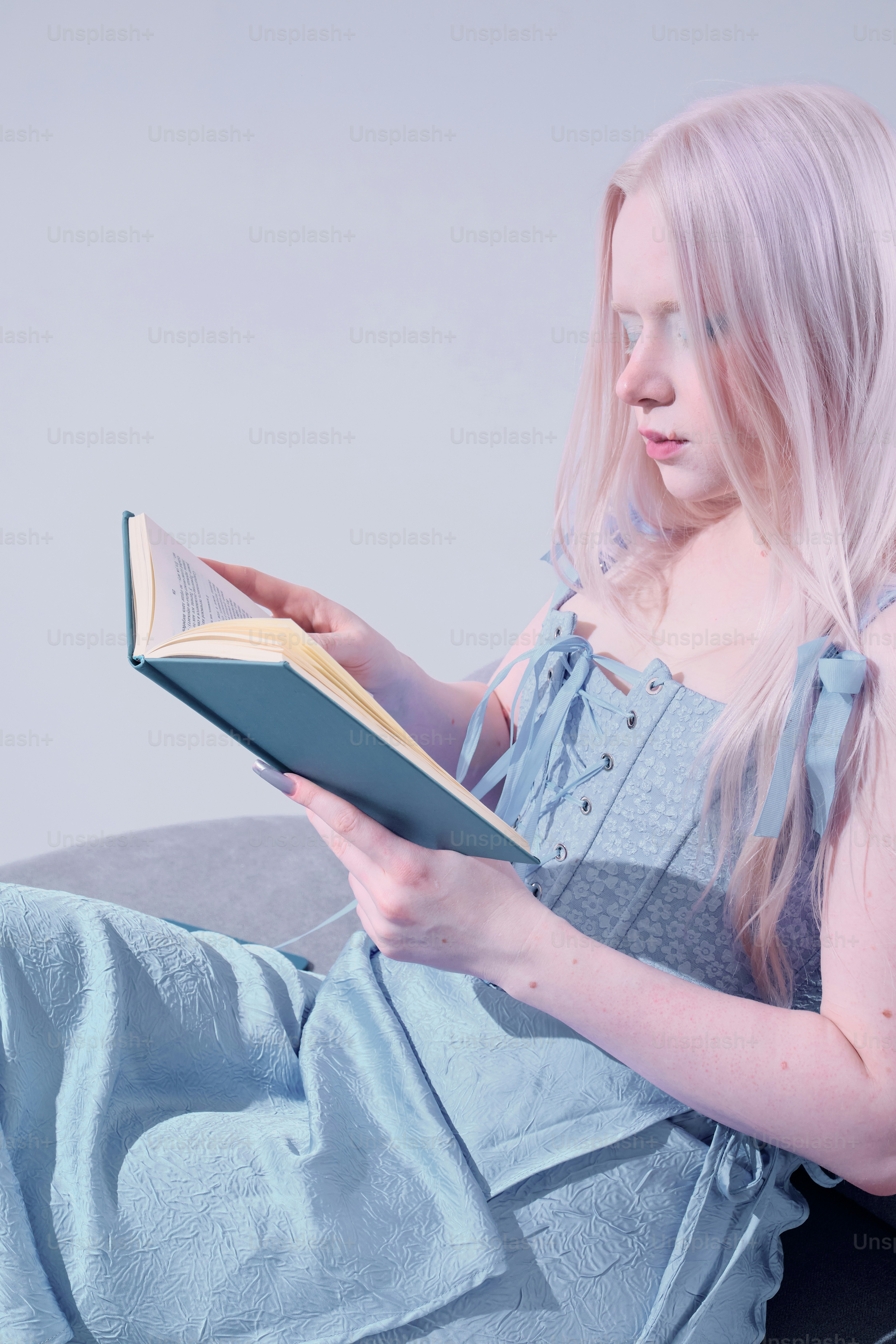 Una joven con rasgos albinos lee un libro.