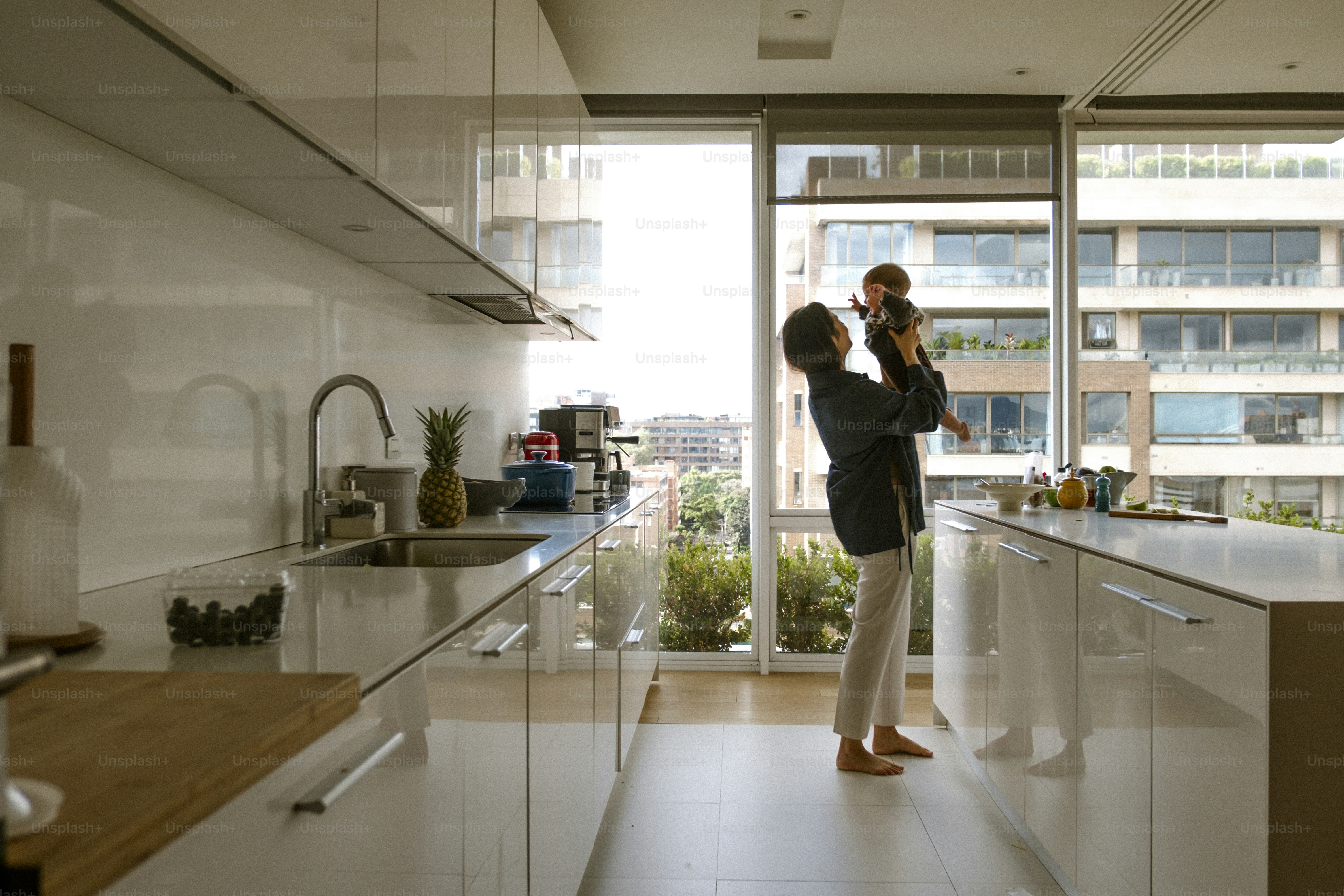 Person holding a baby in a modern kitchen.