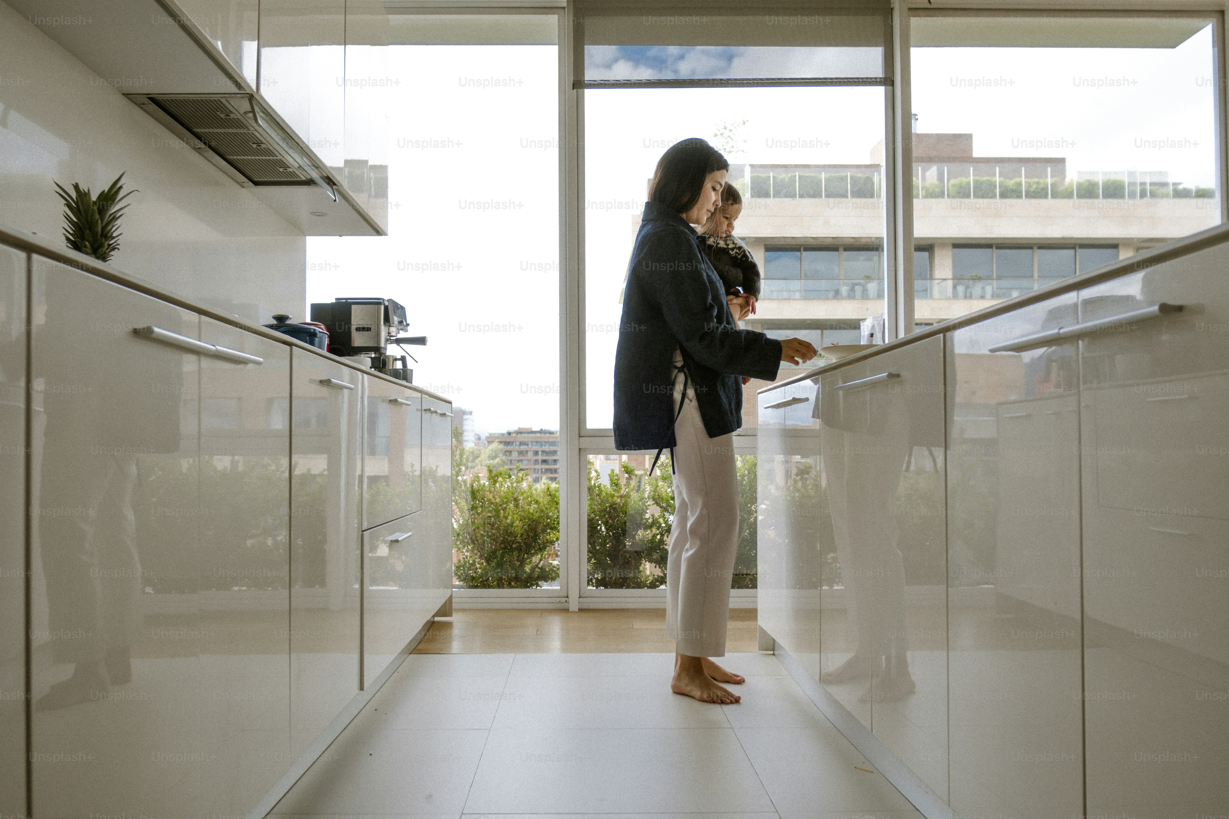 Woman standing in a modern, glossy white kitchen.