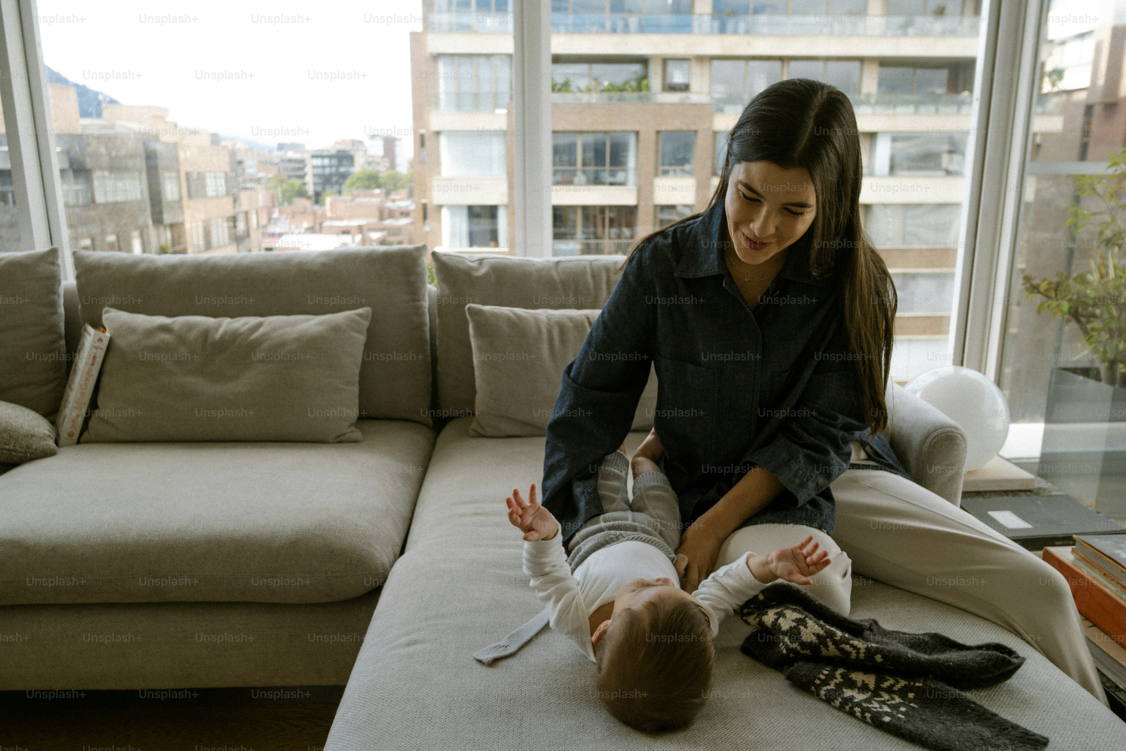Mother dressing her baby on a couch