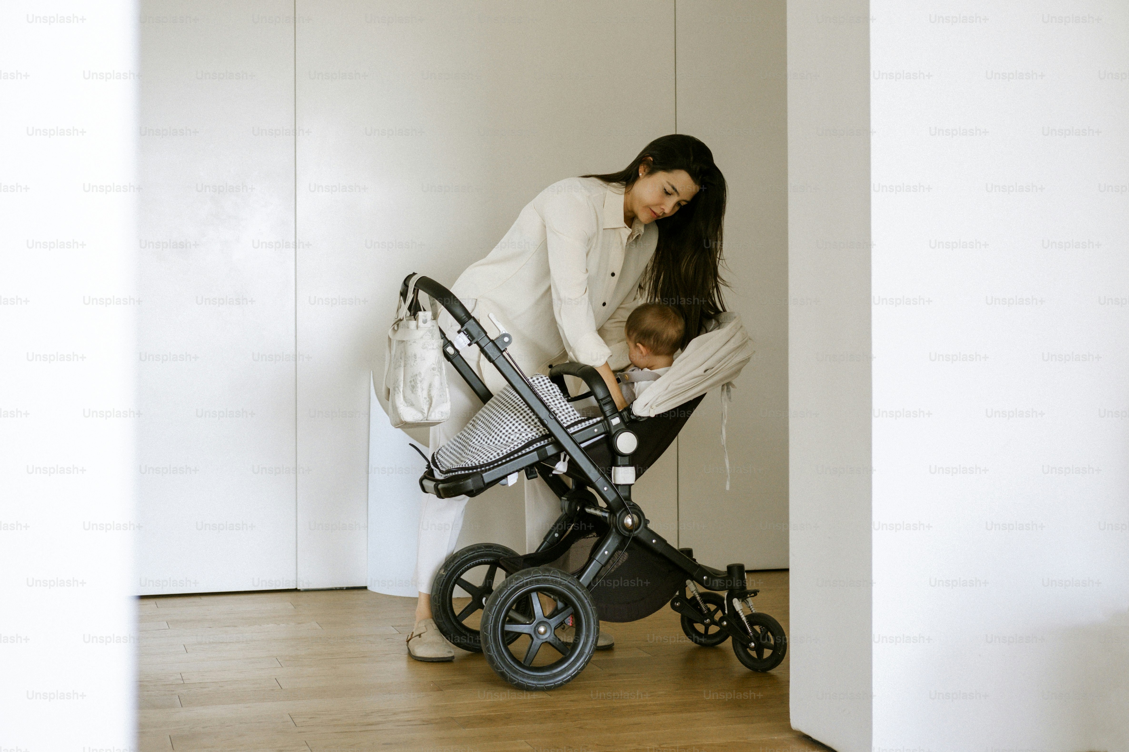 Mother placing baby into a stroller indoors