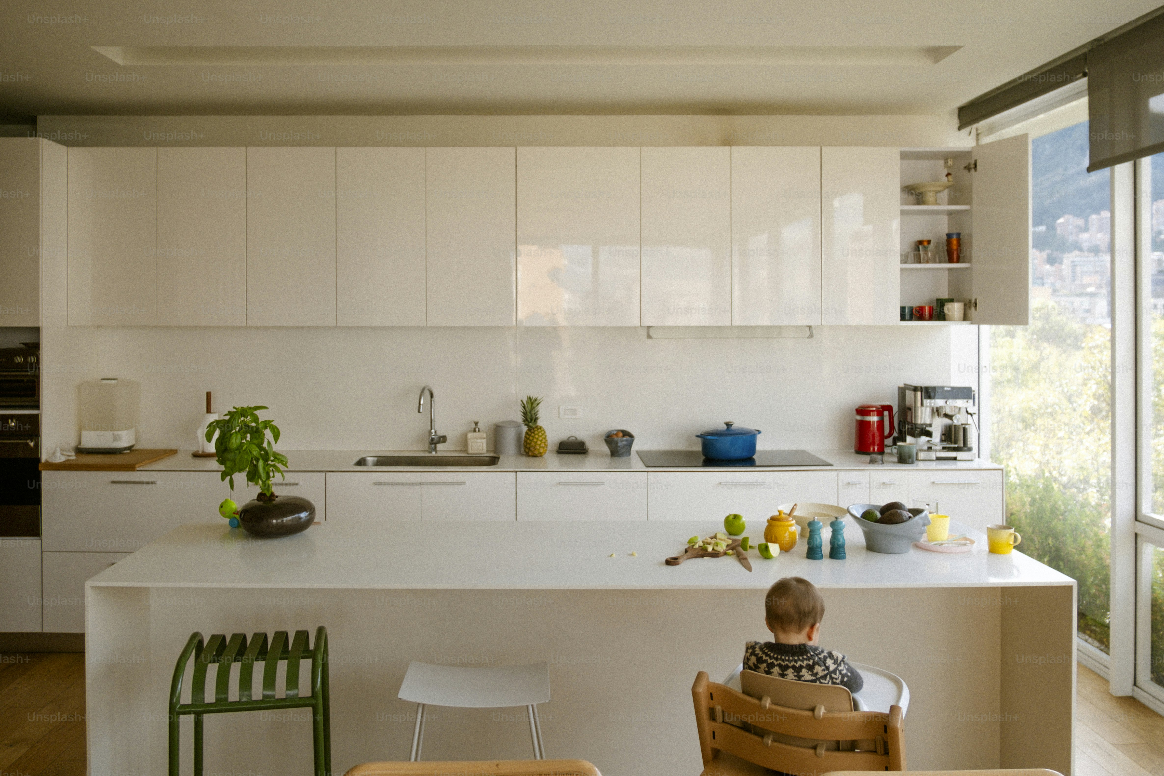 Modern white kitchen with island and child sitting.