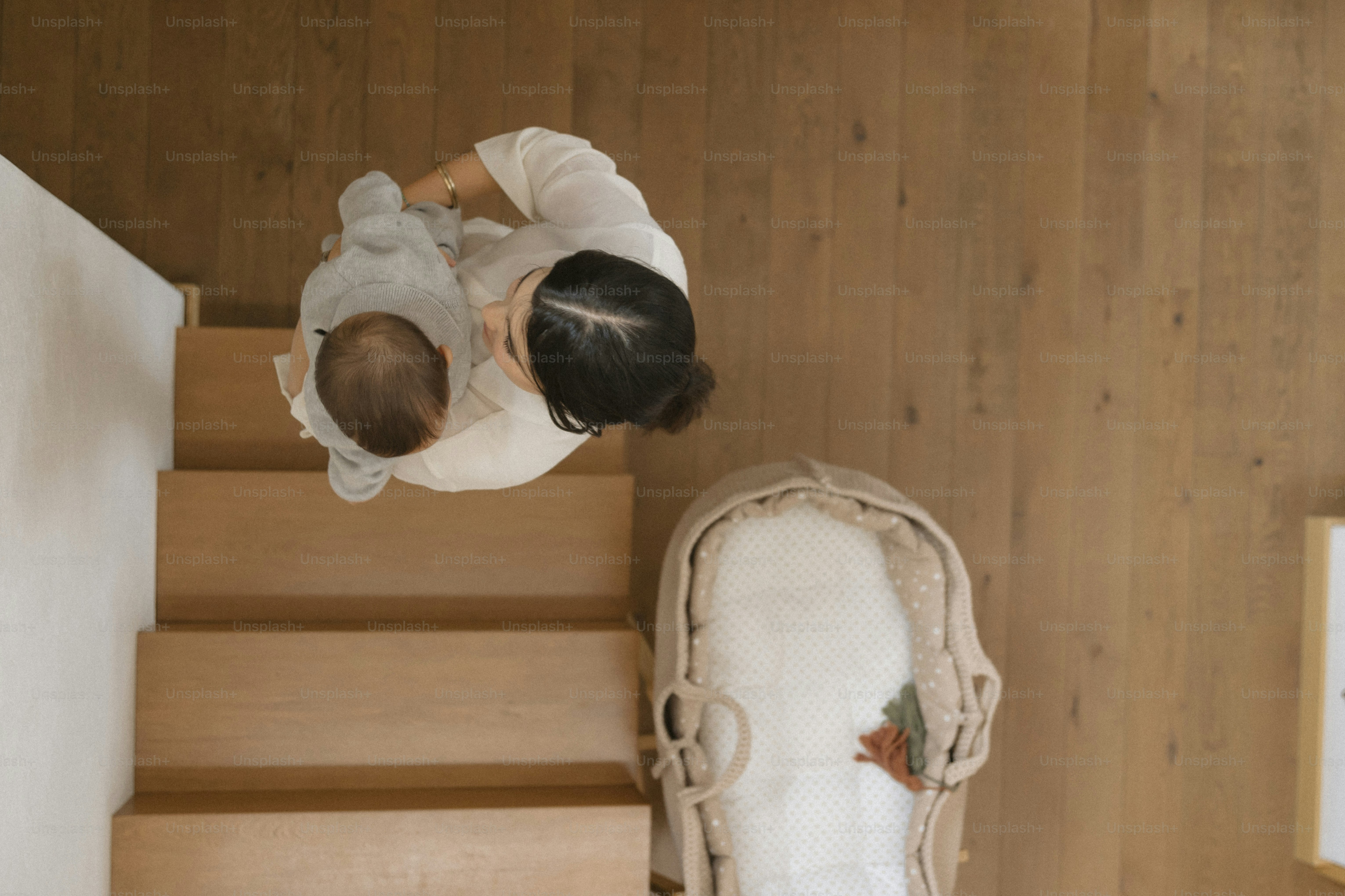 A woman and baby walk up wooden stairs