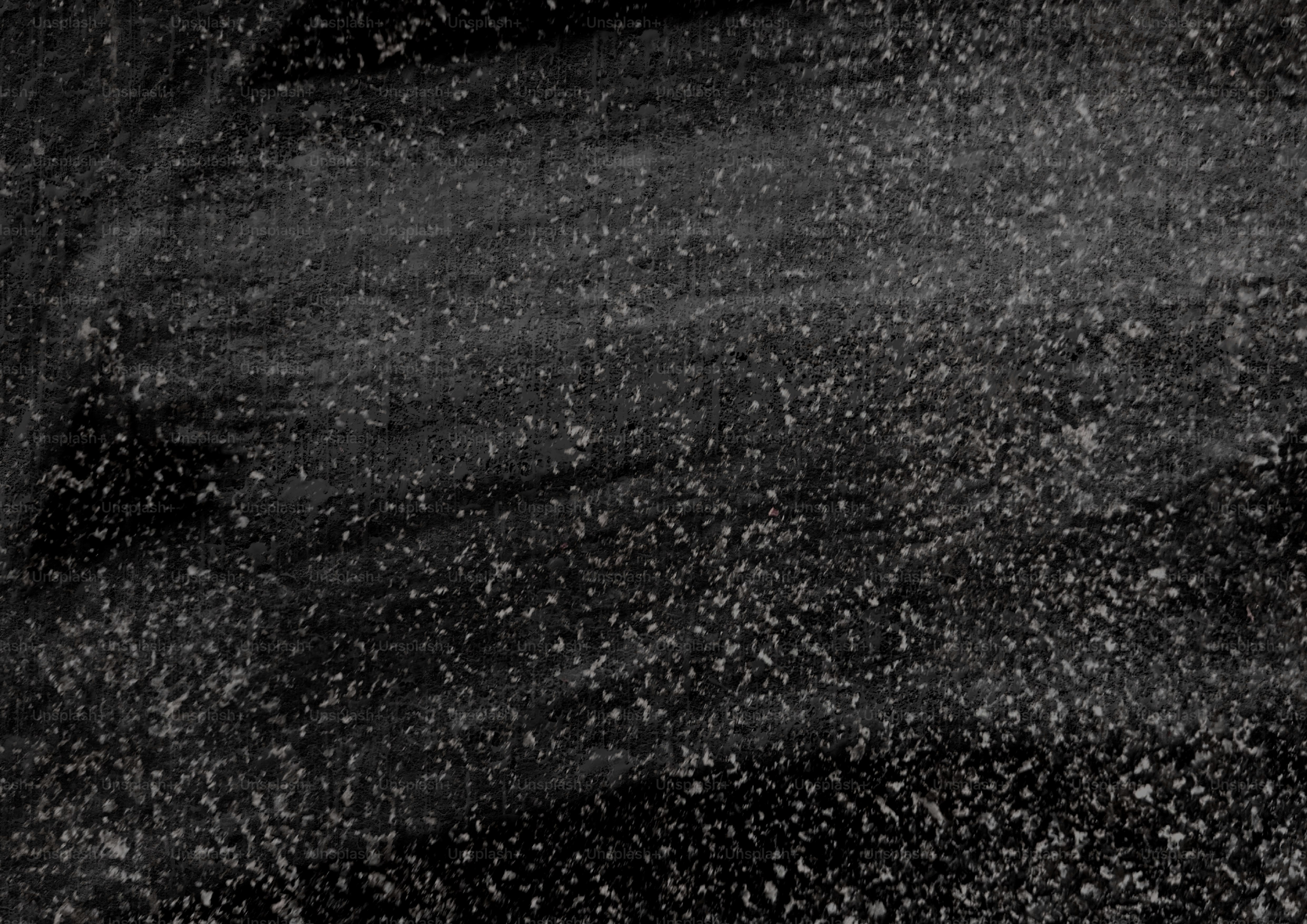 Nahaufnahme einer strukturierten dunkelgrauen Oberfläche mit weißen Sprenkeln