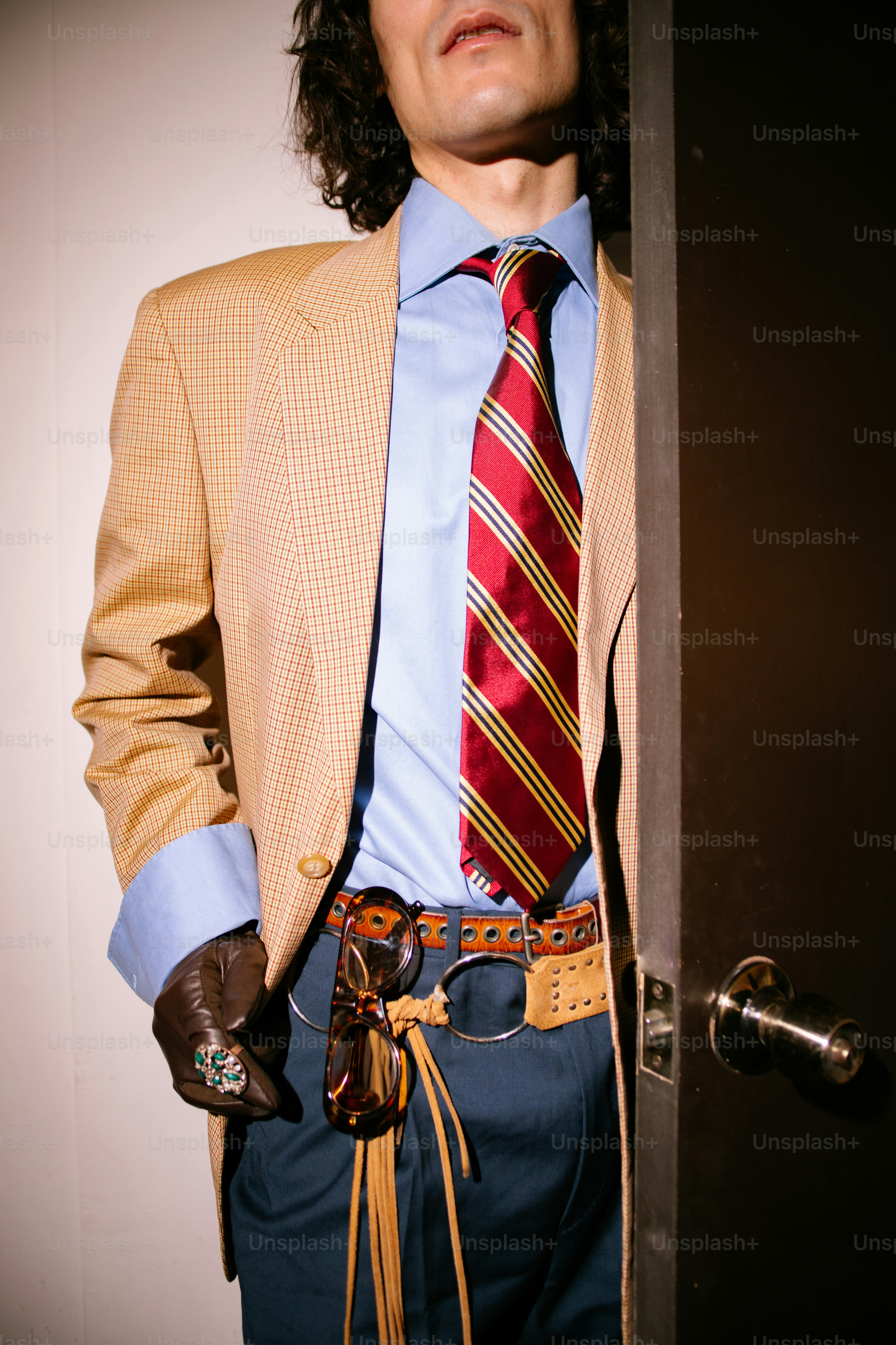 Man in tan blazer, blue shirt, and striped tie.