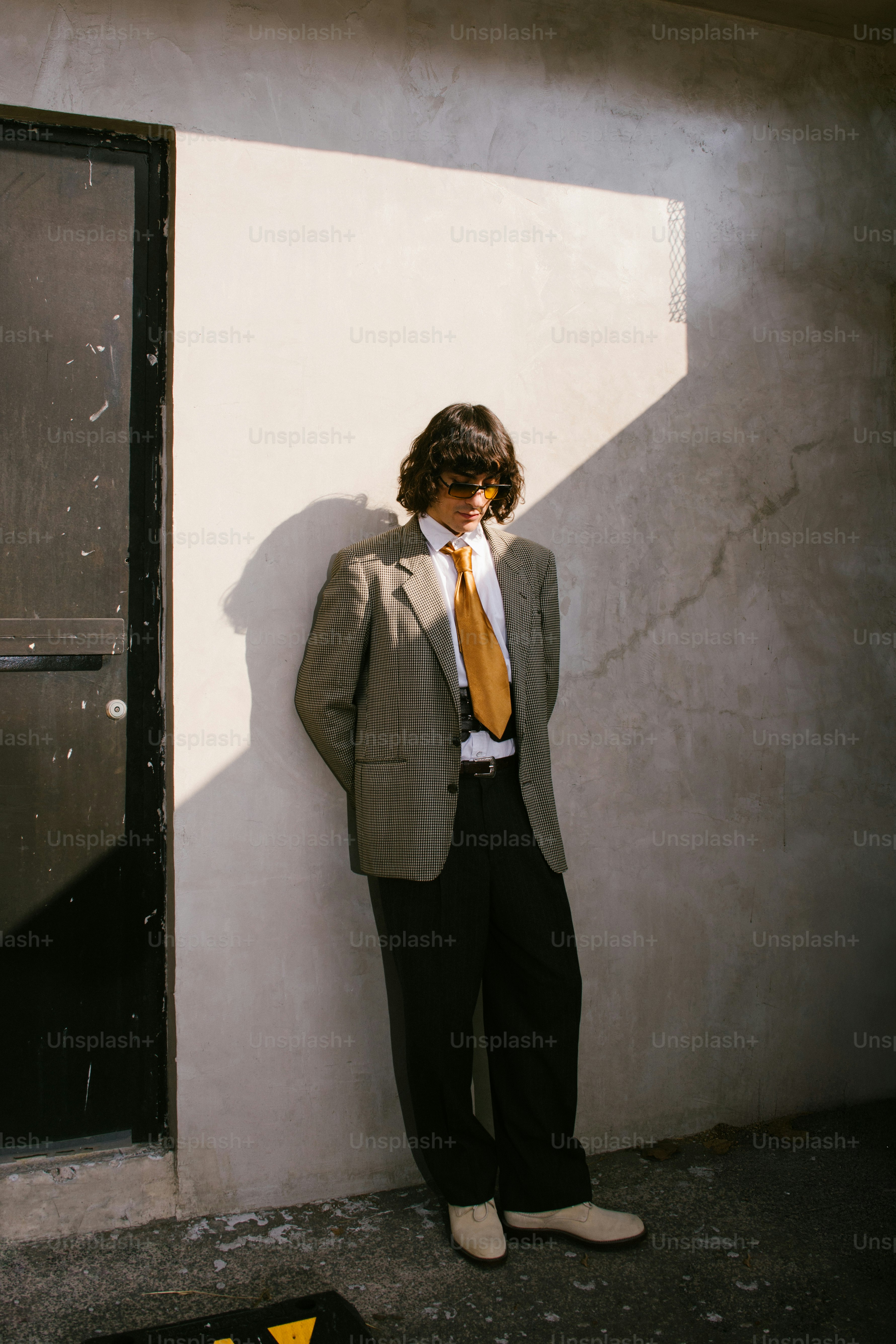 Ein junger Mann im Anzug lehnt an einer Wand.