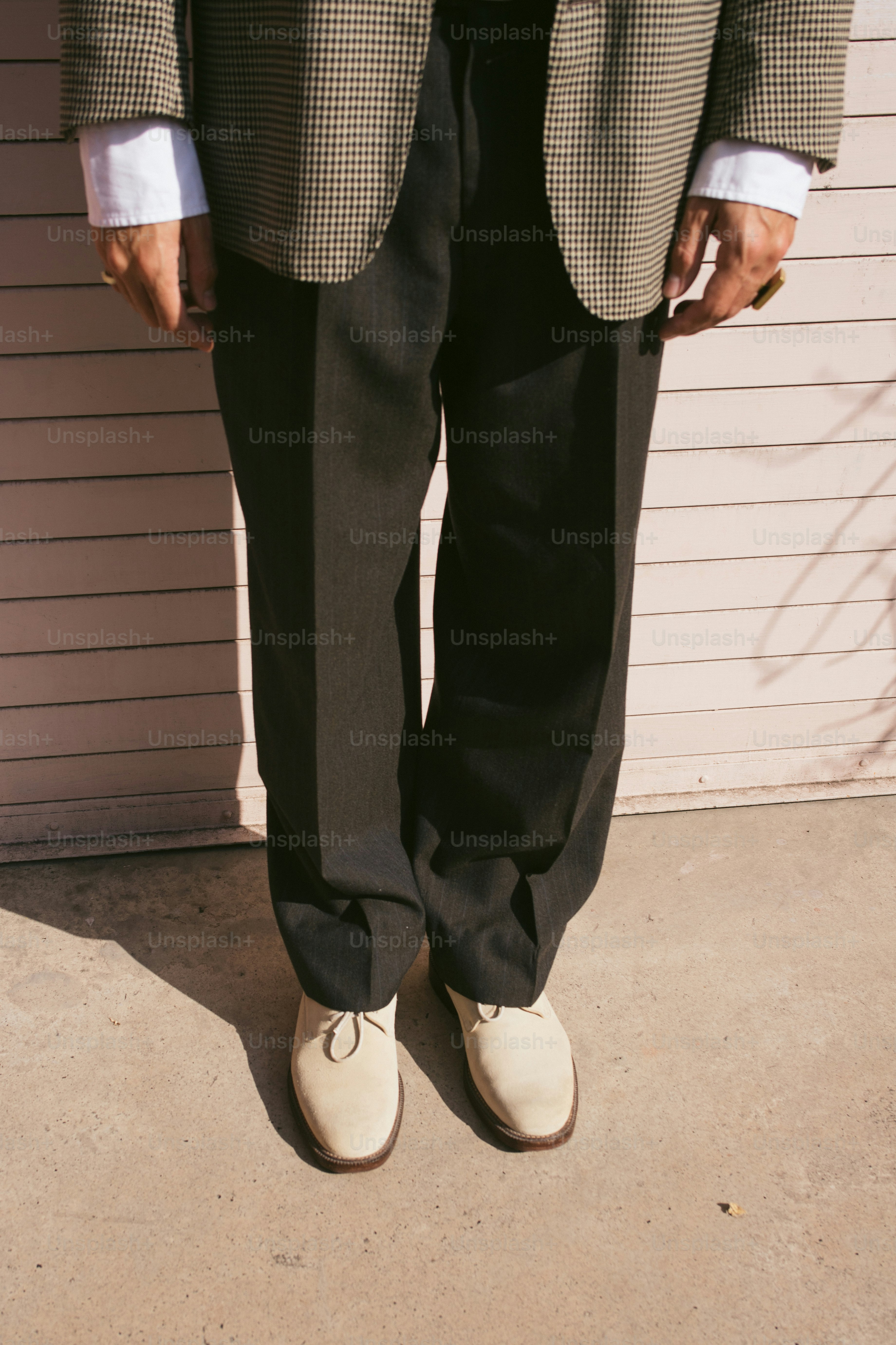 Un uomo in abito e scarpe chiare sta all'aperto.