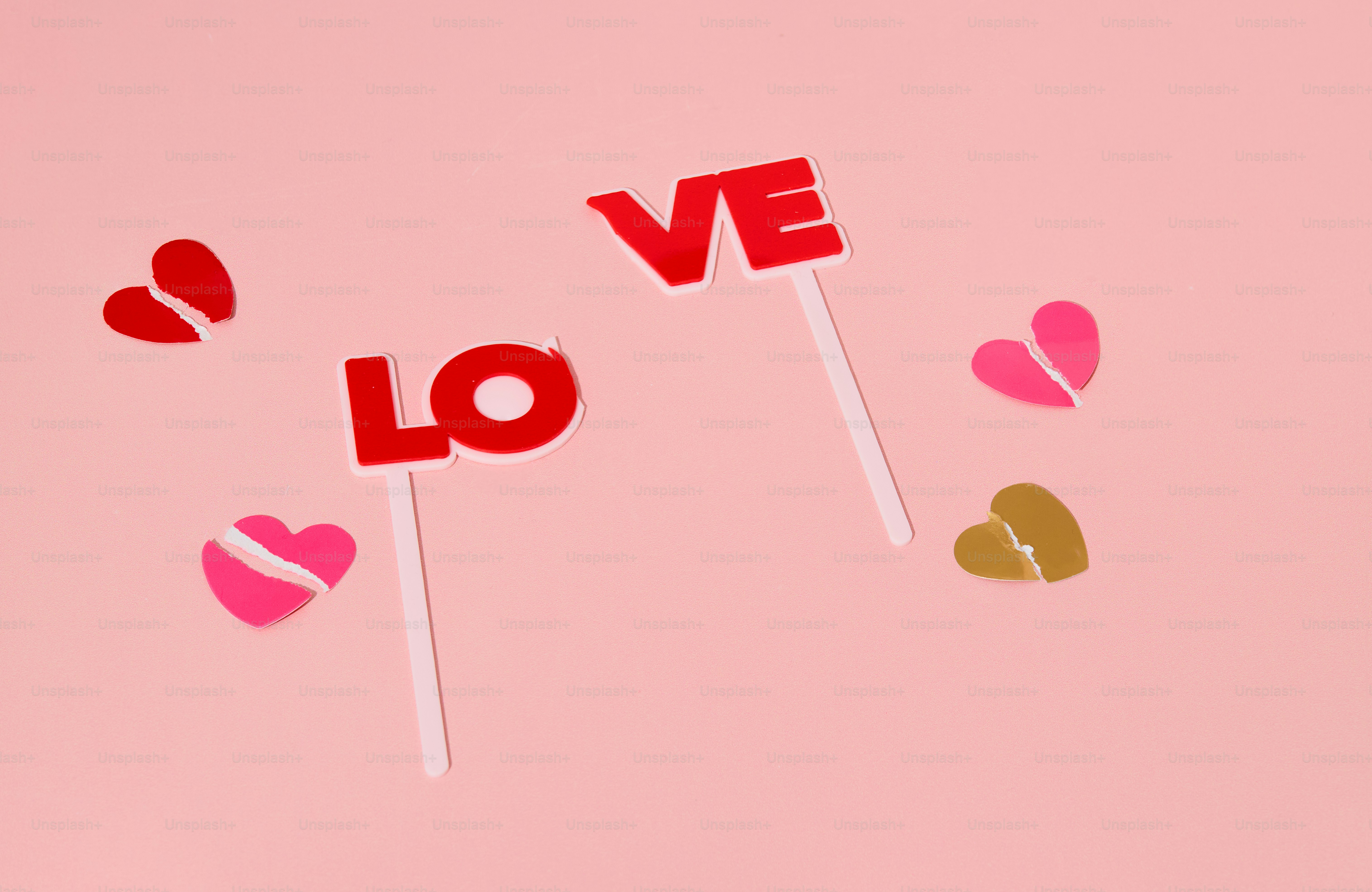 Red letters spell love with broken hearts on pink