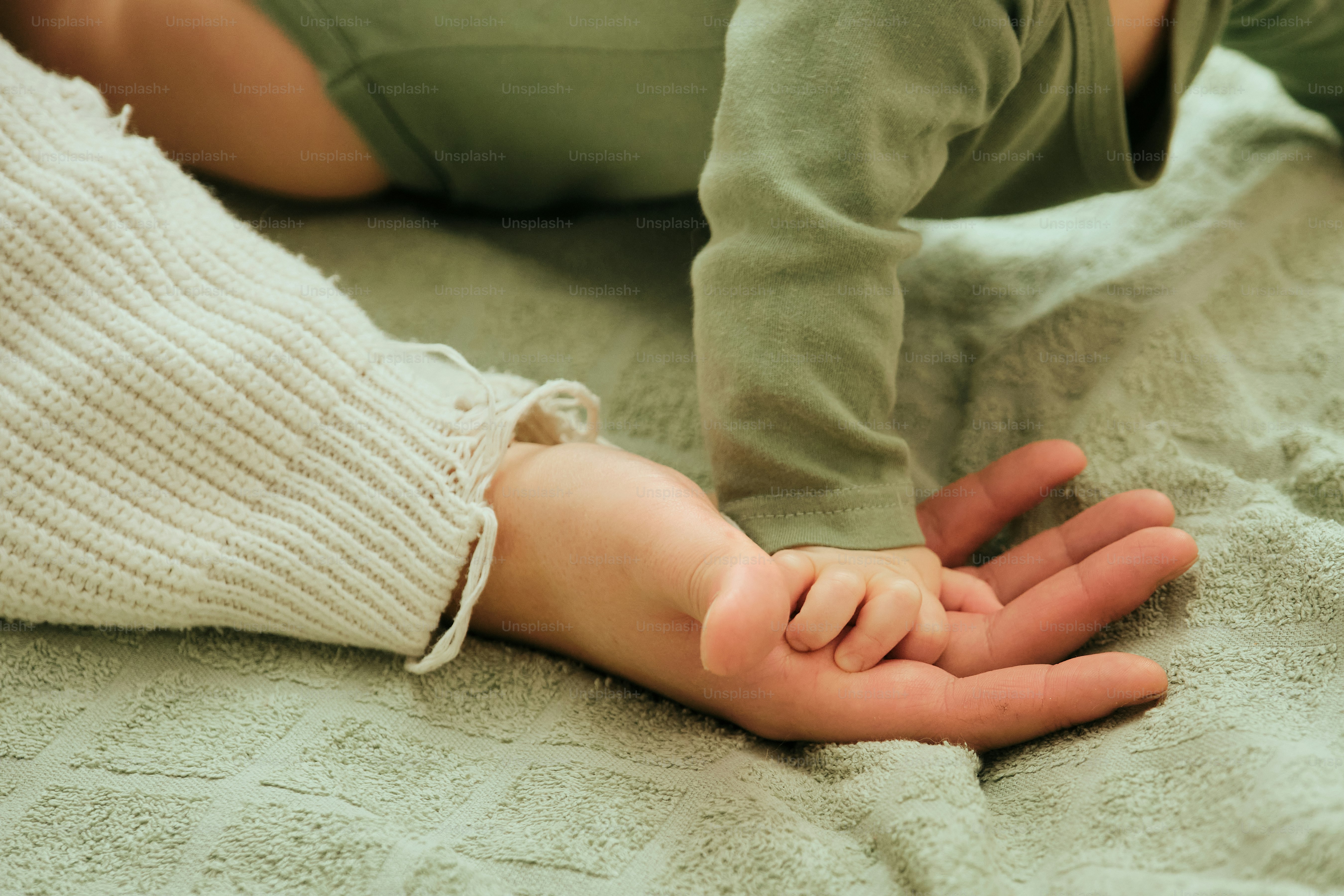 Adult hand holding a baby's tiny hand.