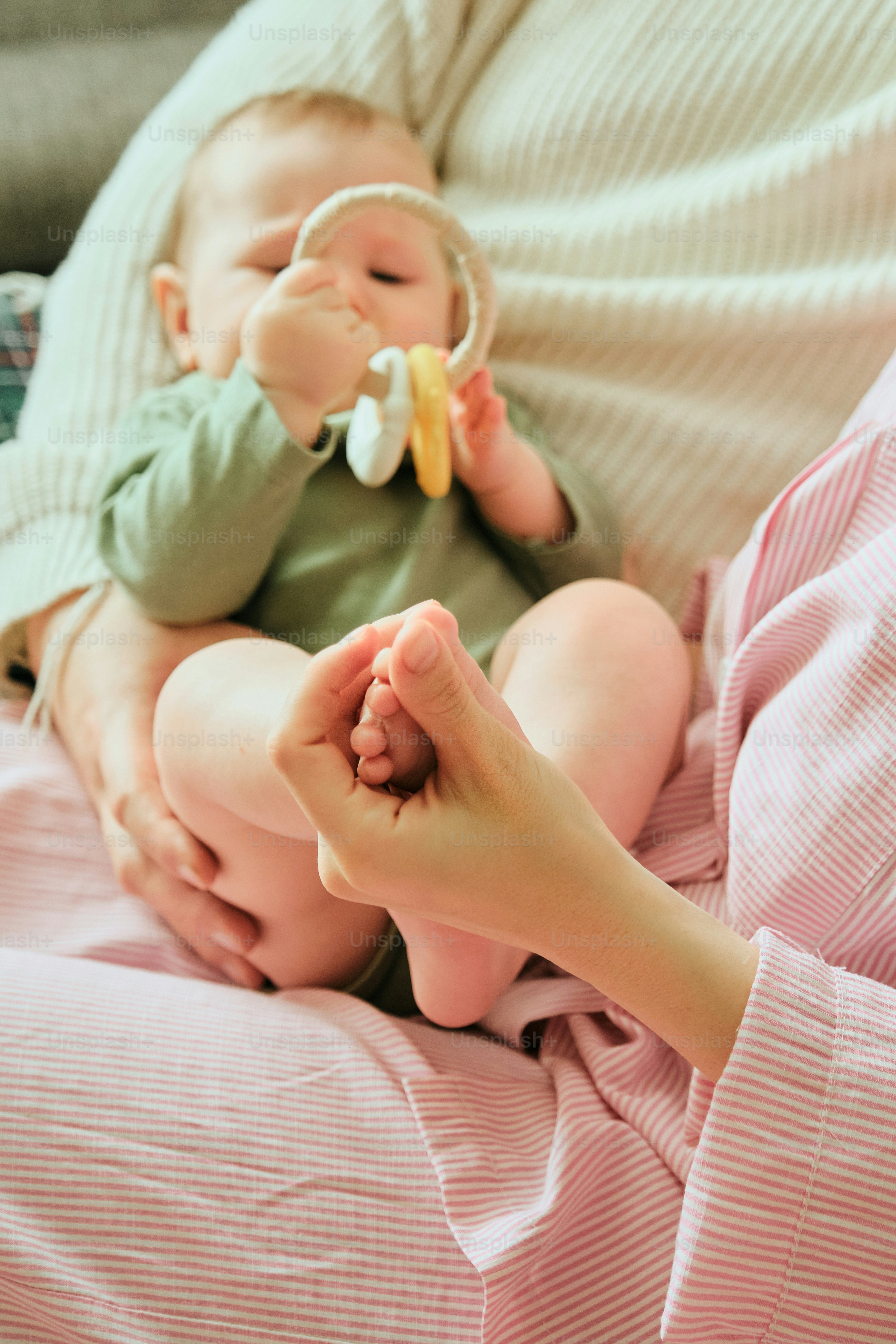 Baby holding a rattle while being held by parent.