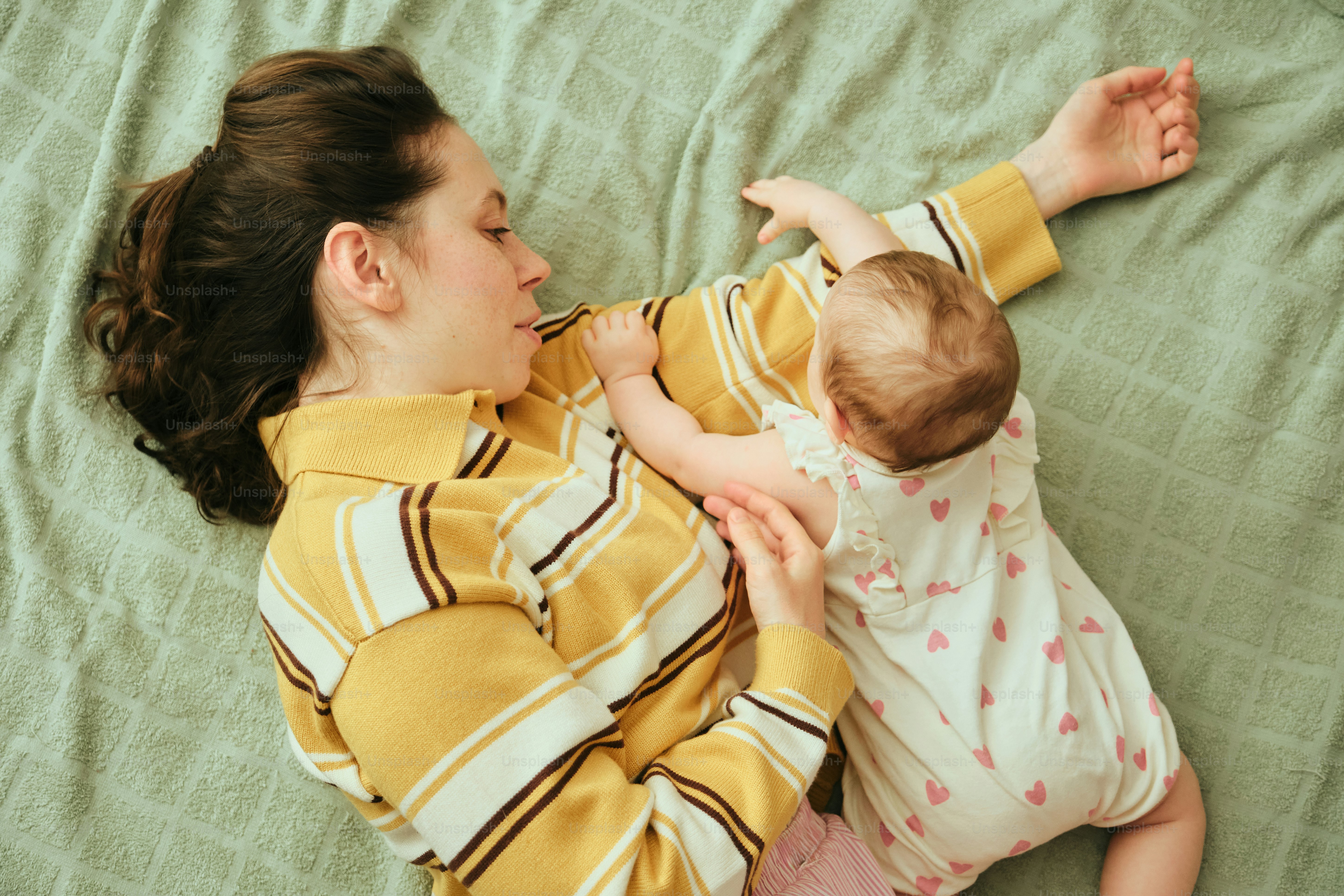 Mother and baby lying on a green textured surface