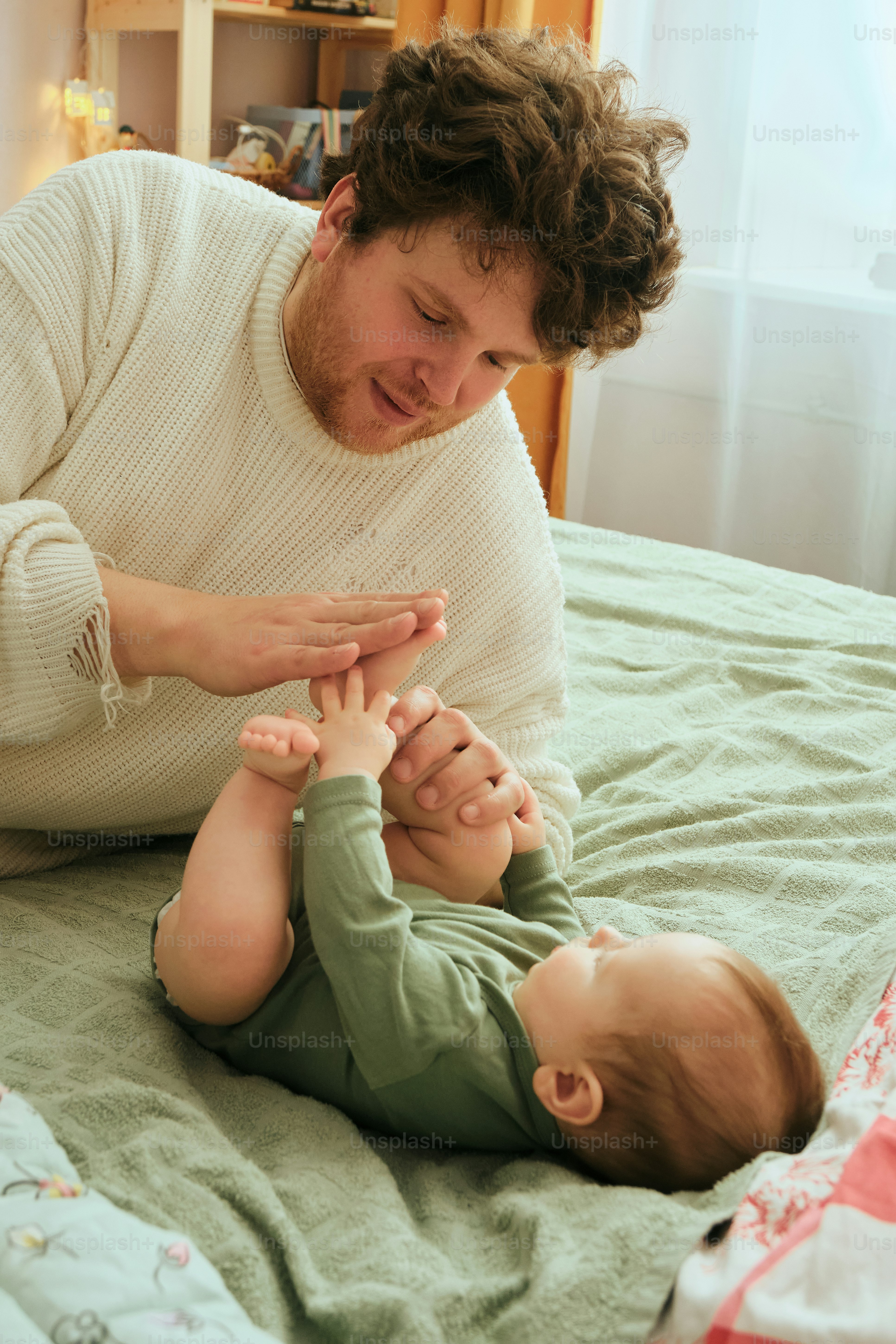 Father gently massages his baby's feet on bed