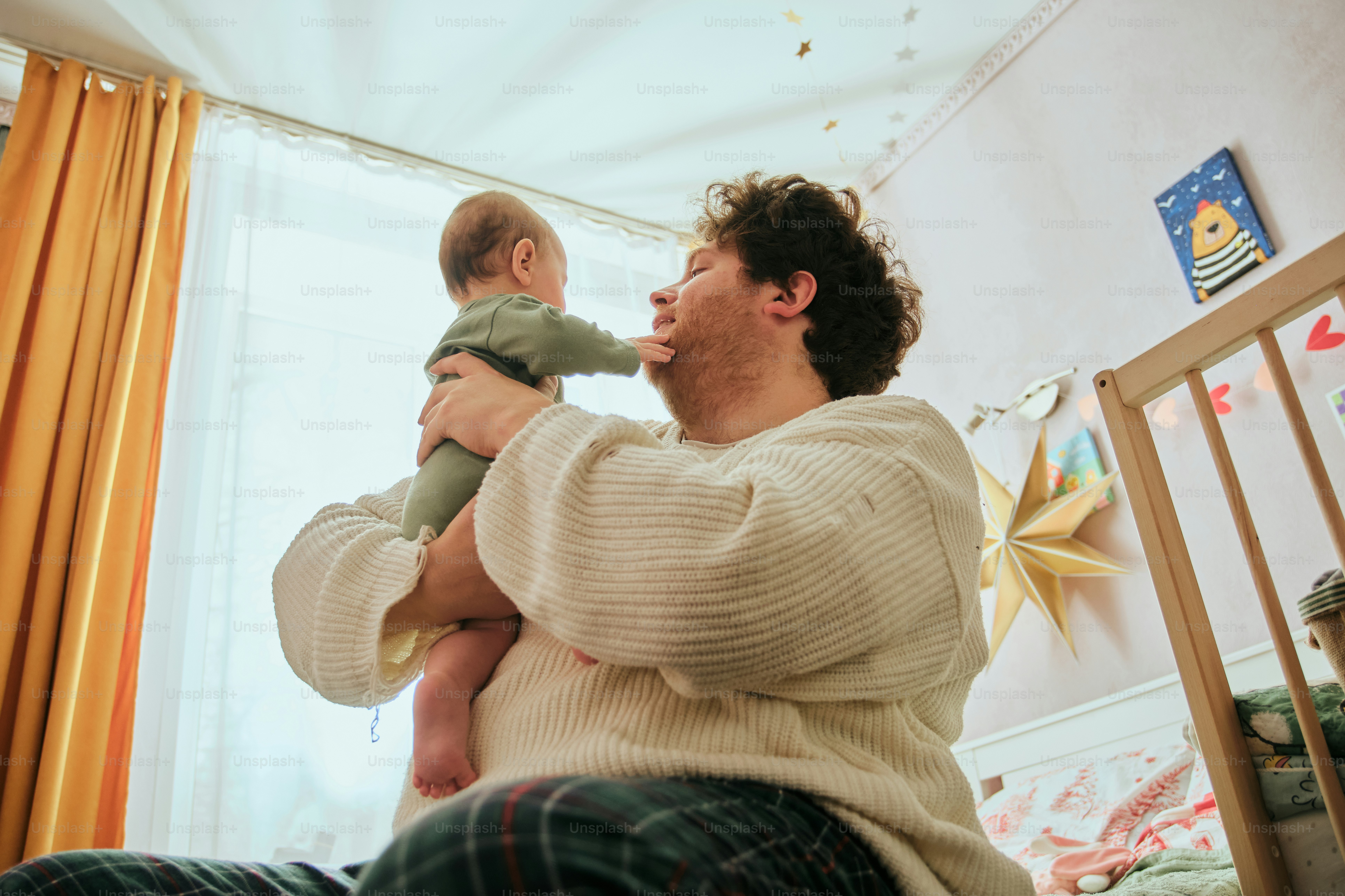 A man holds a baby near a crib