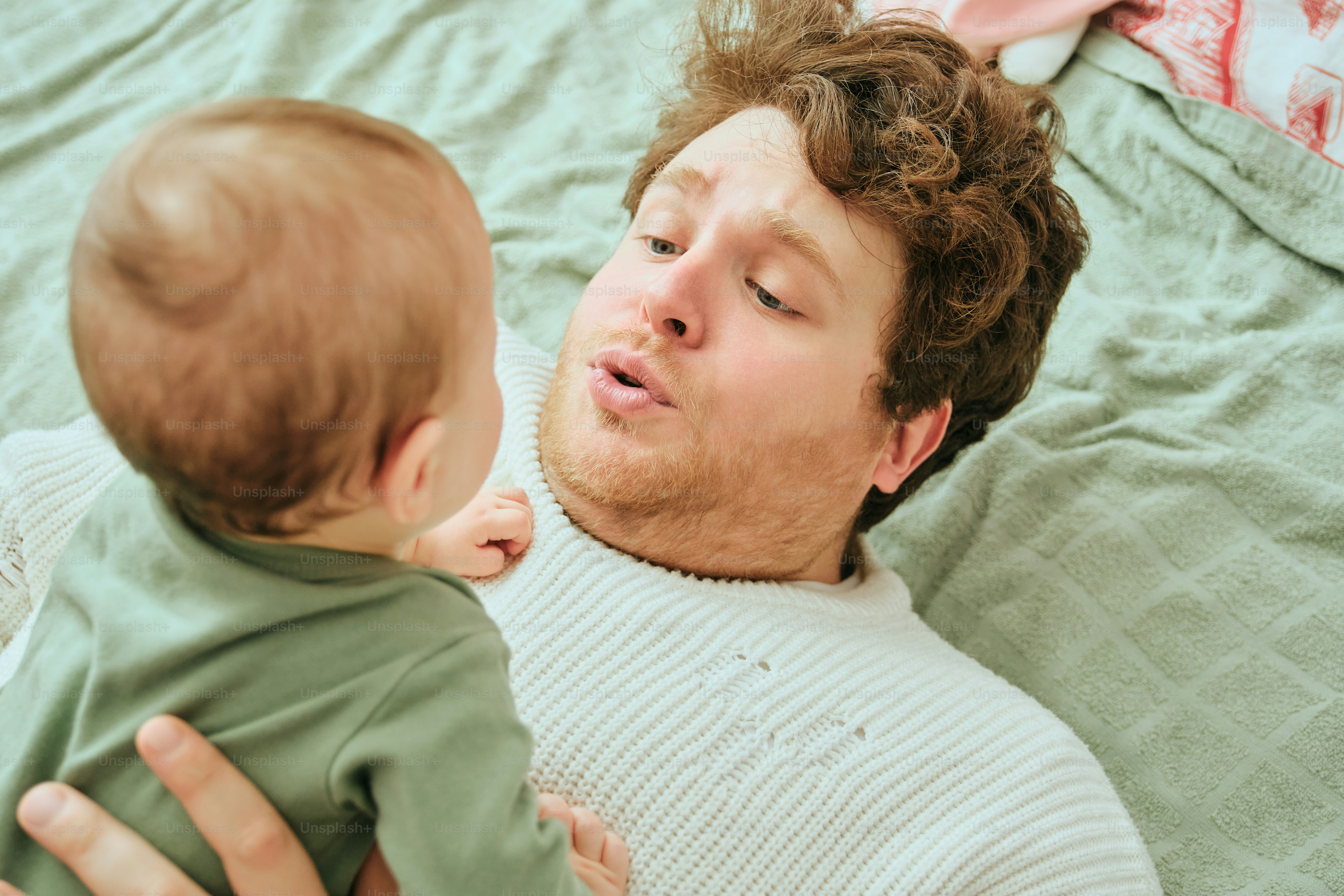 Father and baby looking at each other on a bed