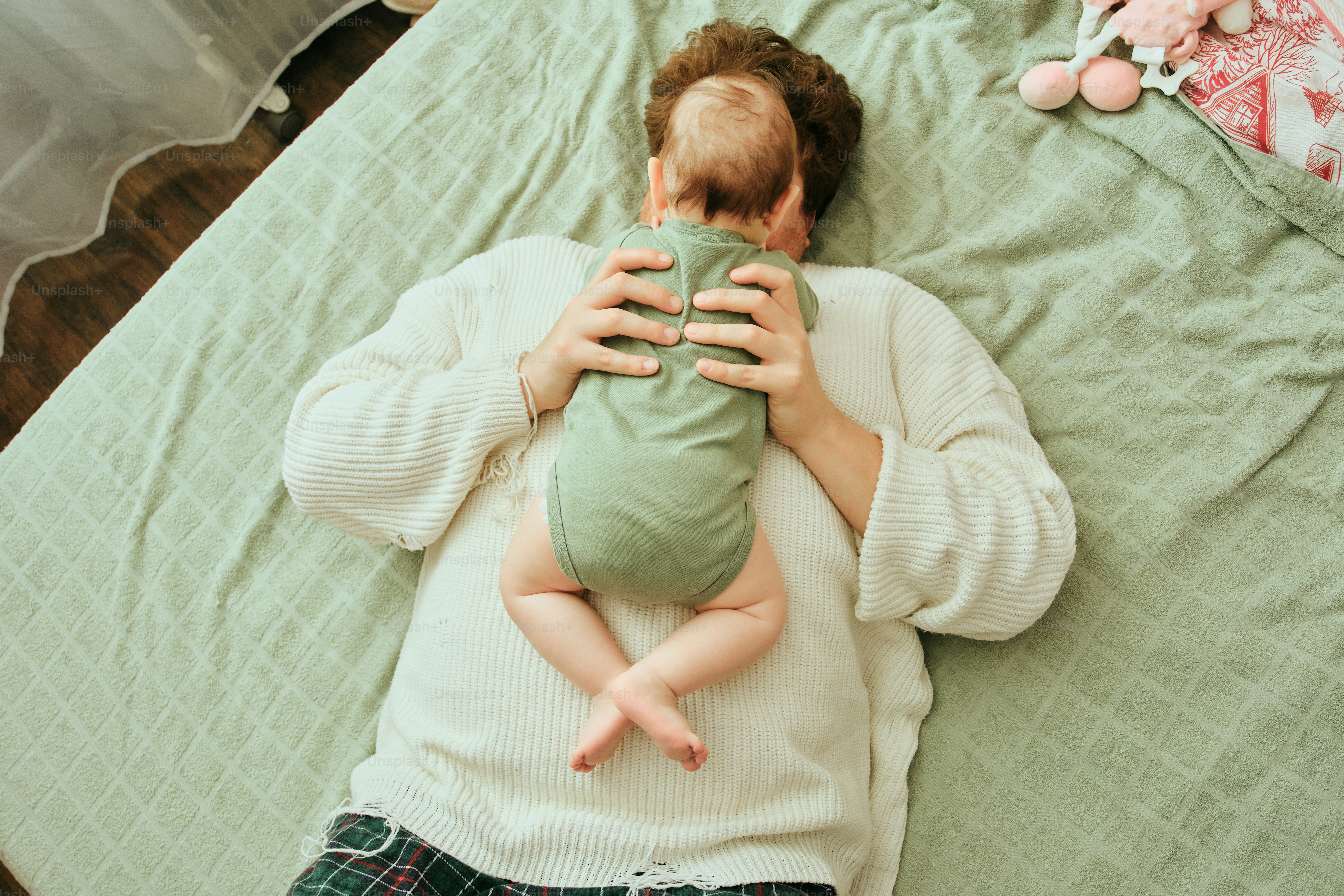 Parent holding a newborn baby on a bed