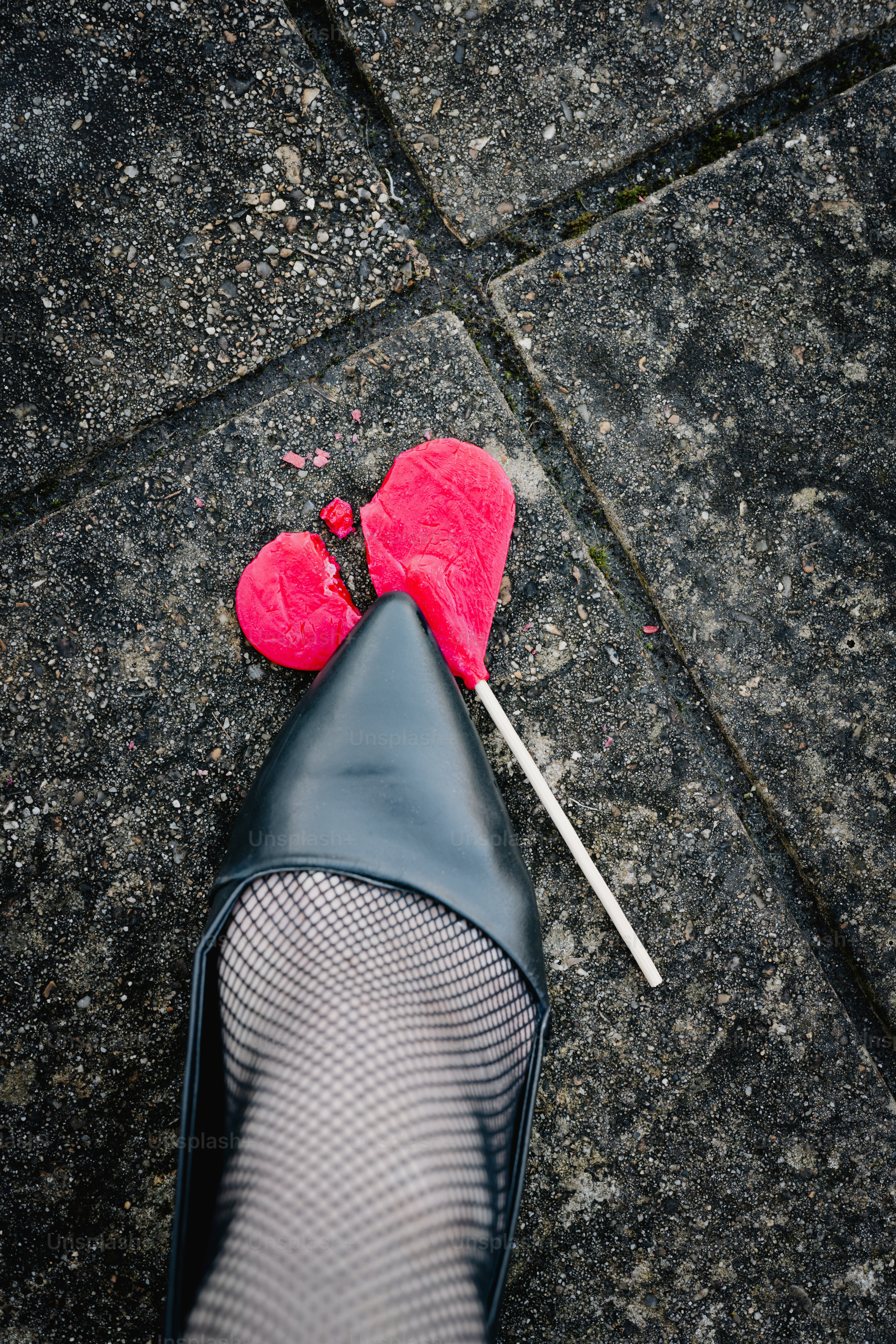 부서진 하트 모양 롤리팝을 짓누르는 신발.