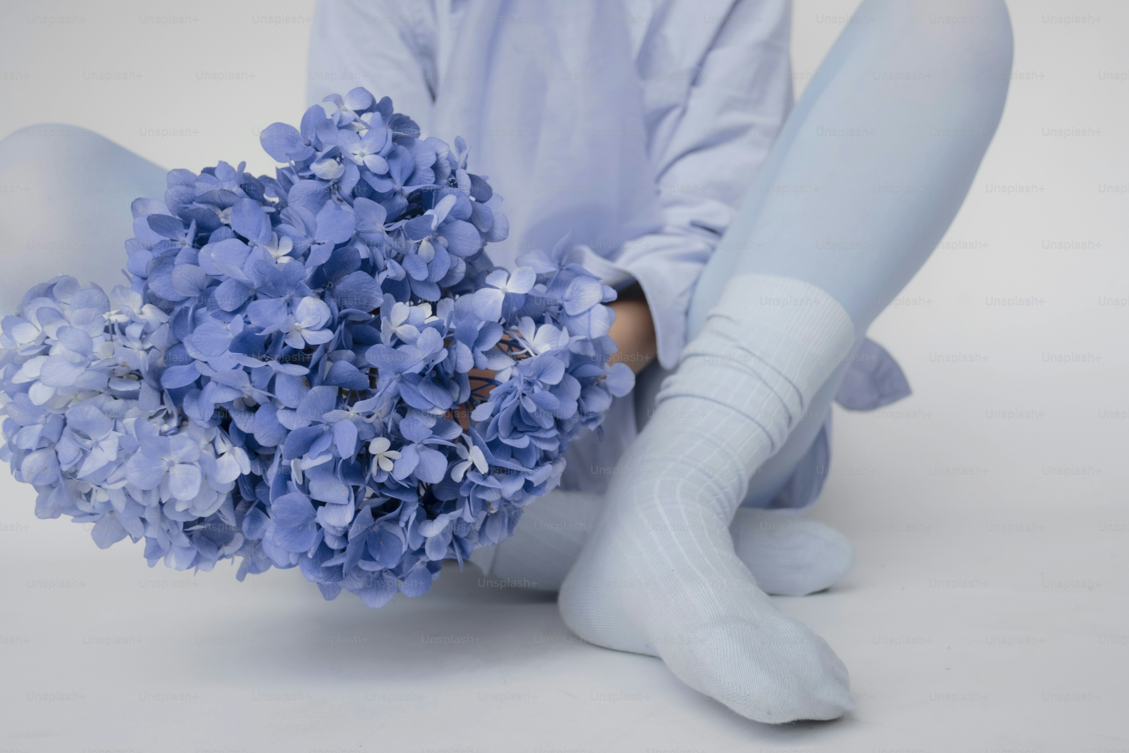 A person in blue holding a bouquet of blue hydrangeas.